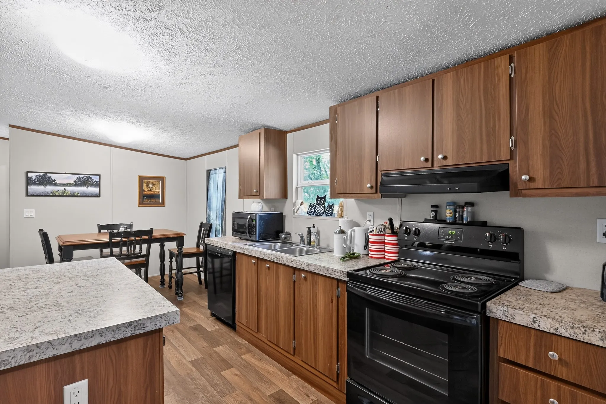Kitchen featuring wood-finish cabinetry, speckled countertops, and wood-finish flooring