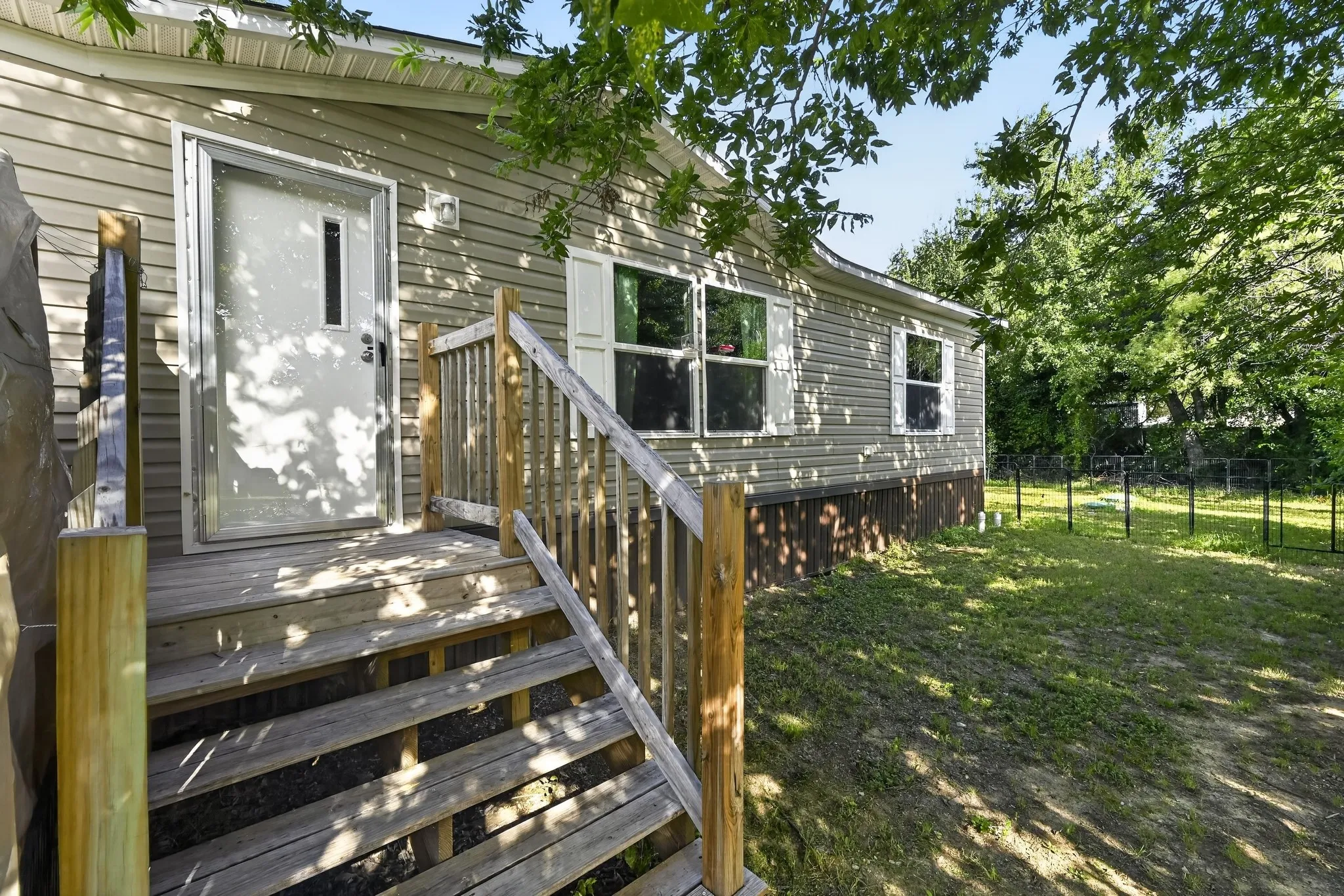 Front exterior featuring horizontal siding, multiple windows with white shutters, and a wood entry deck with railings