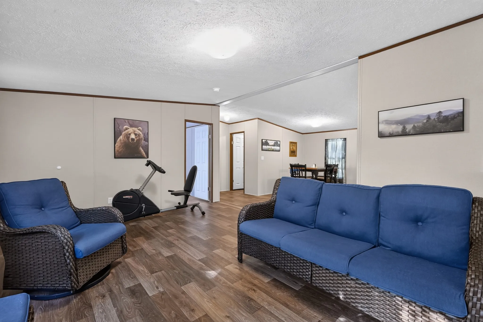 Open-concept living area with wood-finish flooring, neutral wall tones, and crown molding accents