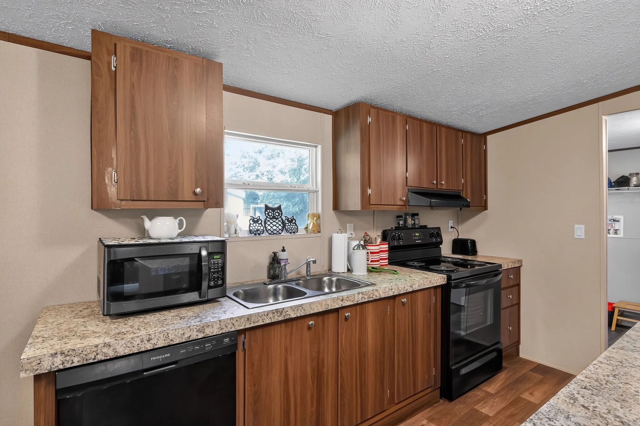 Kitchen featuring wood-finish cabinetry, speckled countertops, and a double basin stainless steel sink