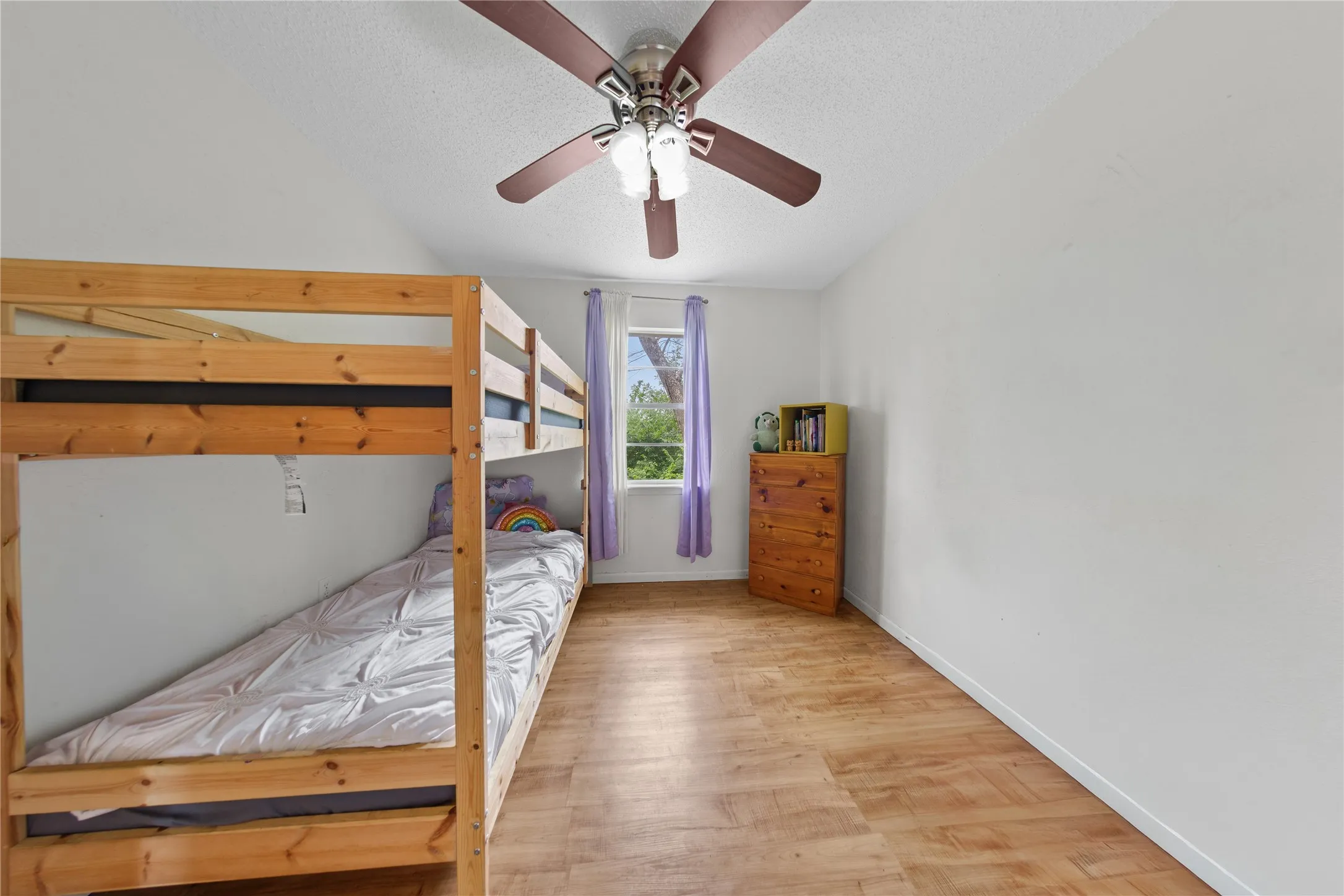 Bright room featuring wood-finish flooring and a ceiling fan with integrated lighting