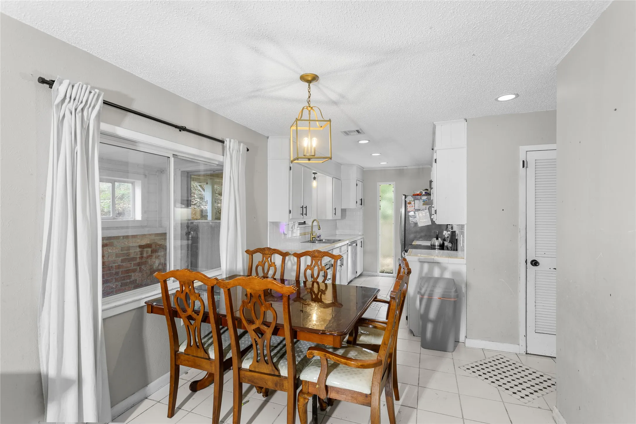 Dining area featuring a contemporary brass chandelier and a large window
