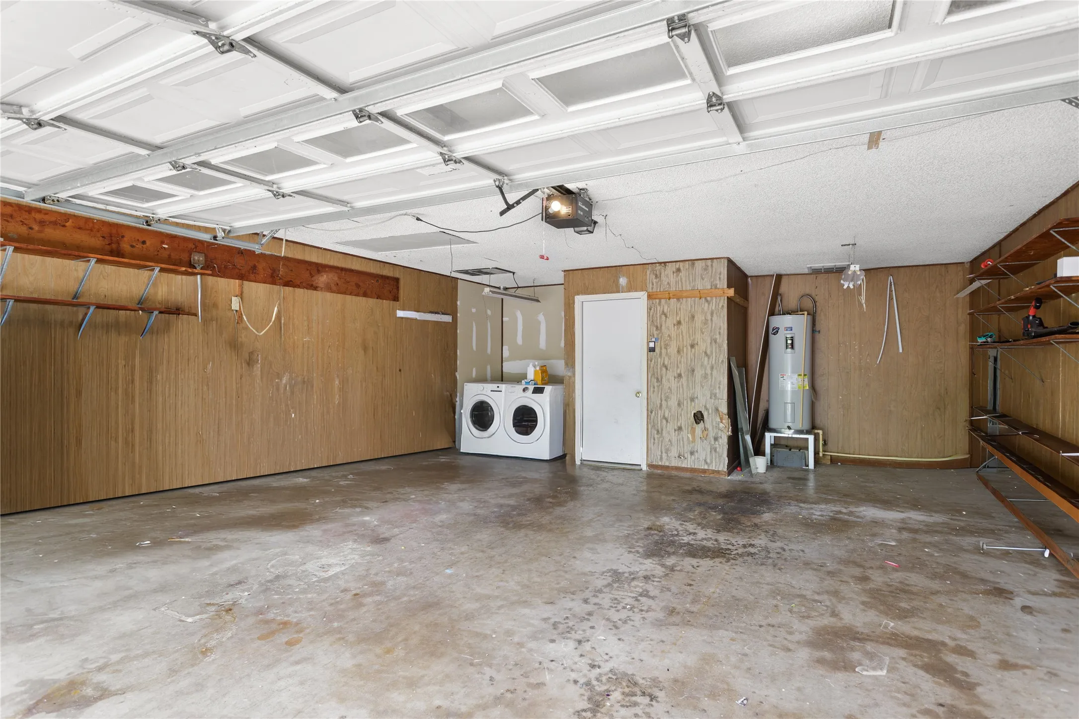 Spacious garage featuring a paneled ceiling, concrete flooring, and built-in shelving