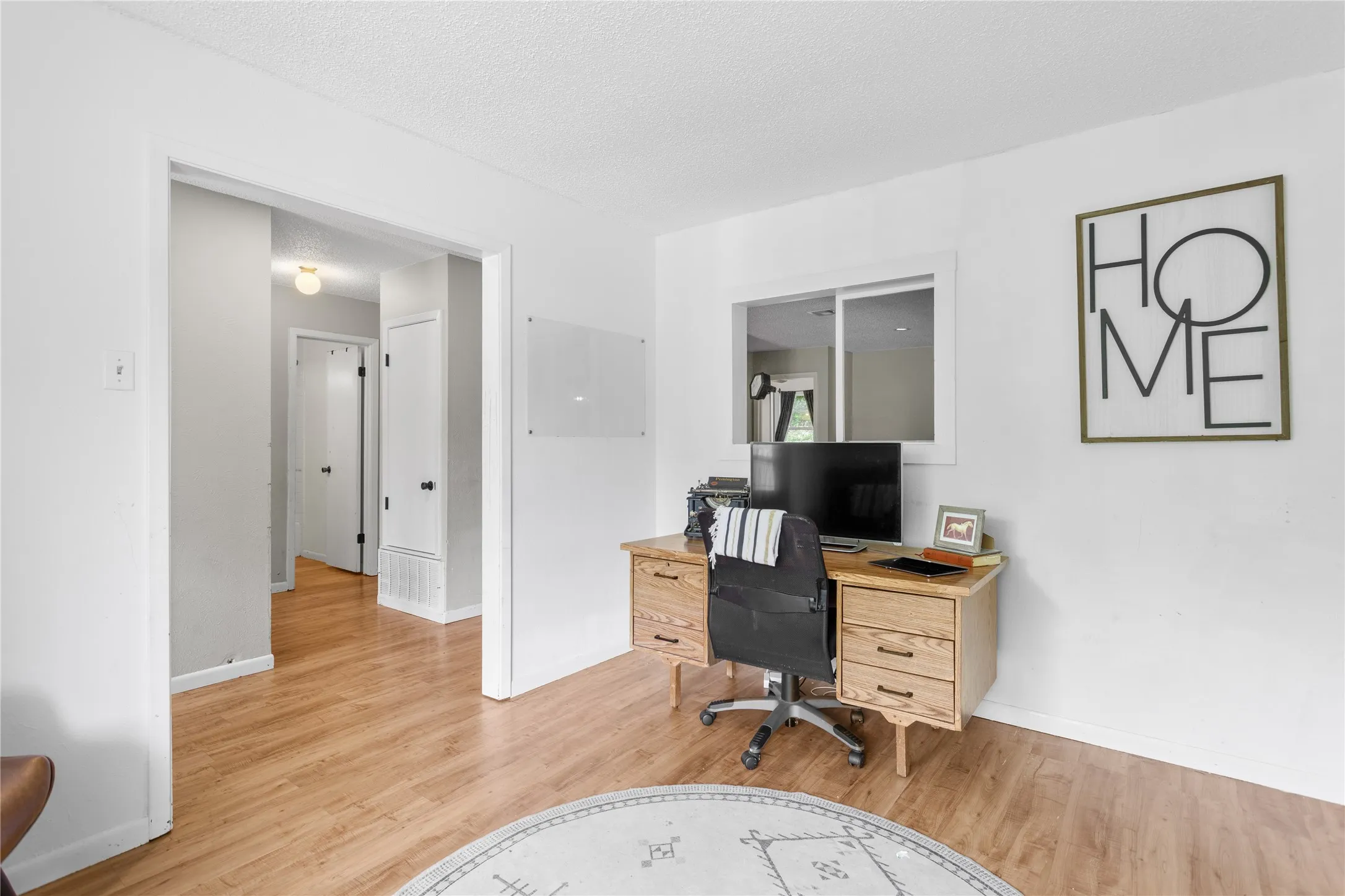 Wood-finish flooring throughout, bright white wall paint, and a white ceiling create a neutral interior palette