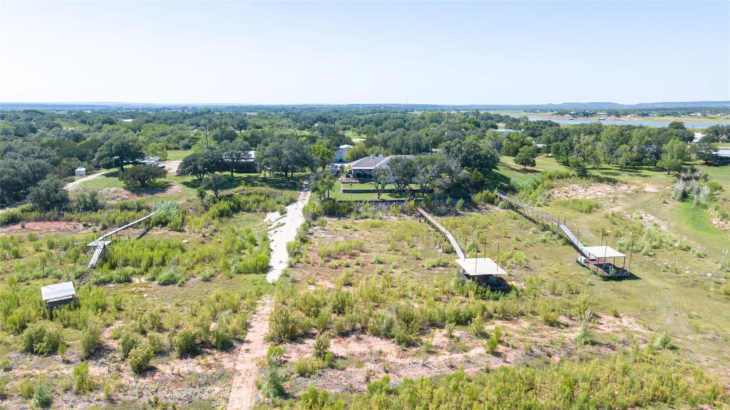 Expansive property featuring three private docks, a gravel path, and mature trees, with additional structures visible among the foliage