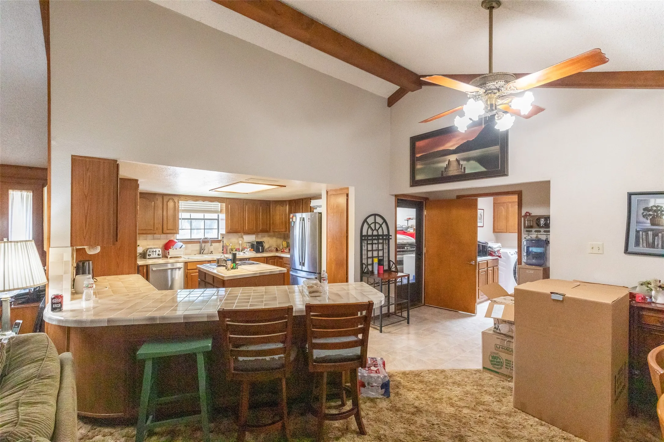 Spacious kitchen featuring wood cabinetry, stainless steel appliances, and a central island with tile countertop