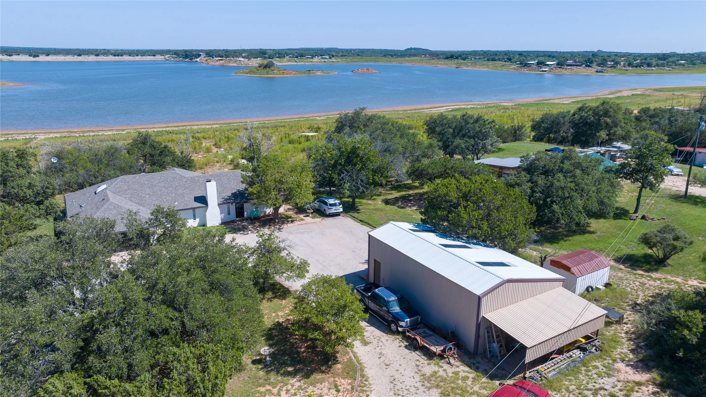 Aerial perspective showcasing a single-story residence with a gray shingle roof and a prominent chimney, situated on a large lot