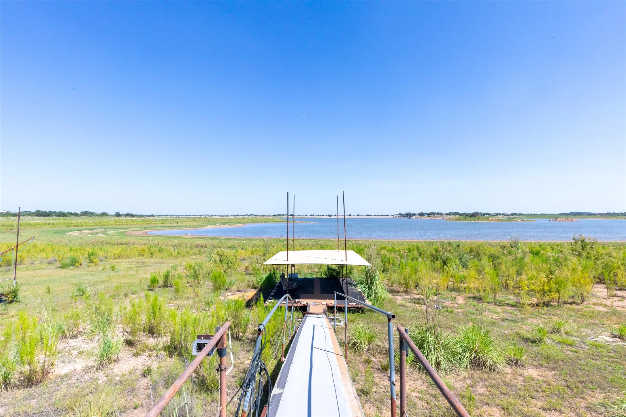 Dock structure with covered boat slip, featuring a walkway with handrails and expansive waterfront