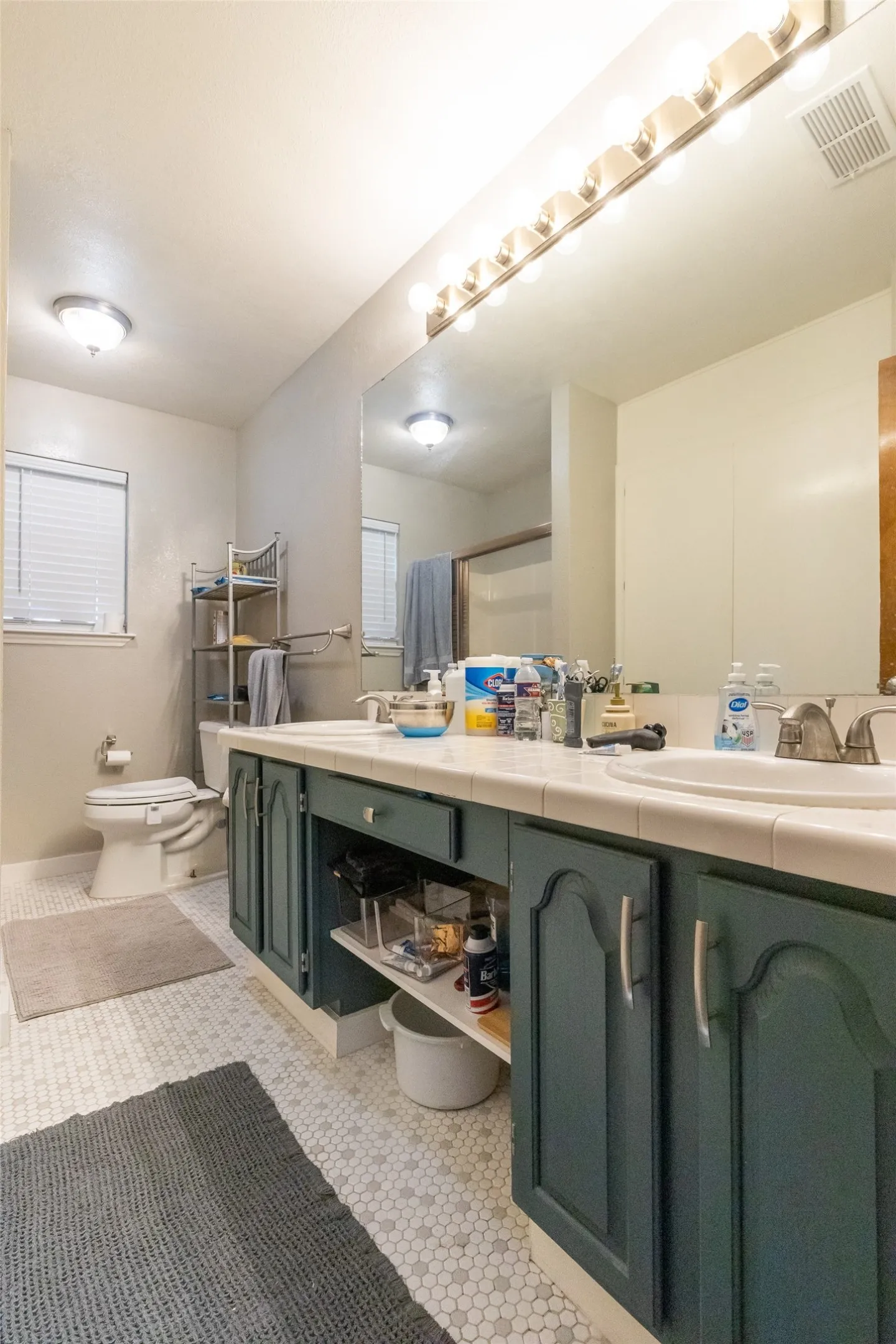 Bathroom featuring a dual vanity with painted cabinetry, white tile countertops, and two integrated sinks