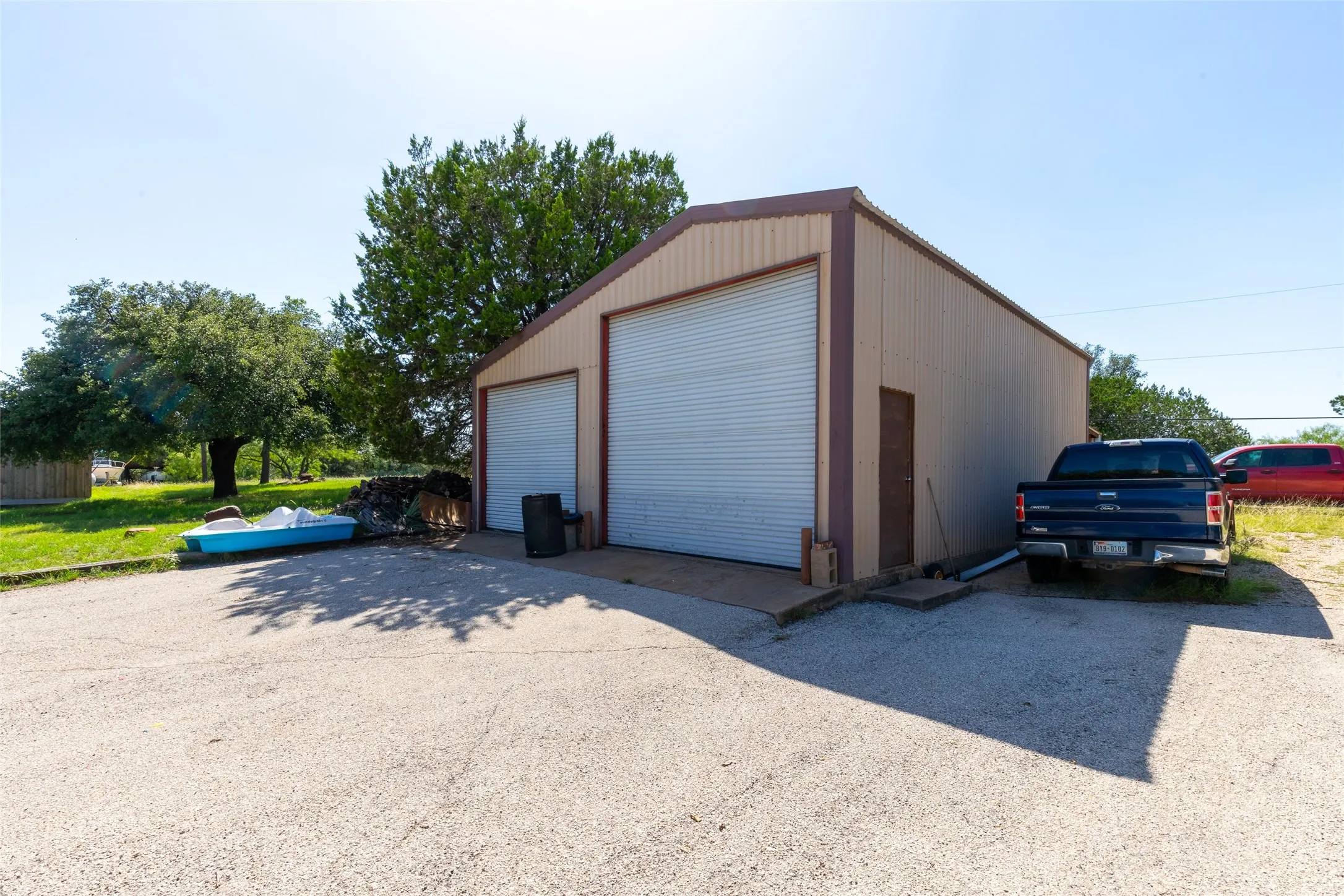 Metal-sided structure featuring two large roll-up garage doors and a separate entry door