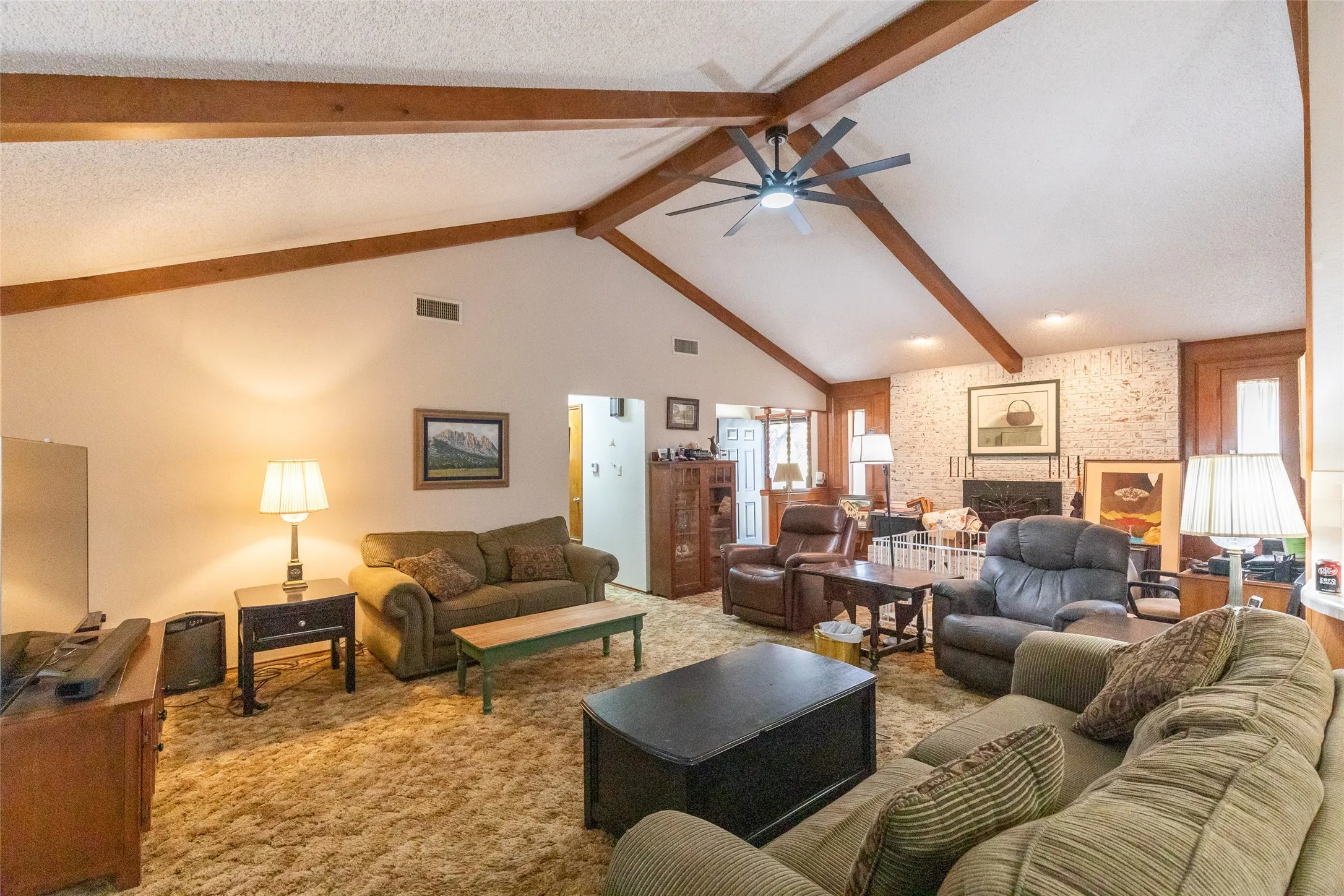 Expansive living space featuring a vaulted ceiling with exposed wood beams