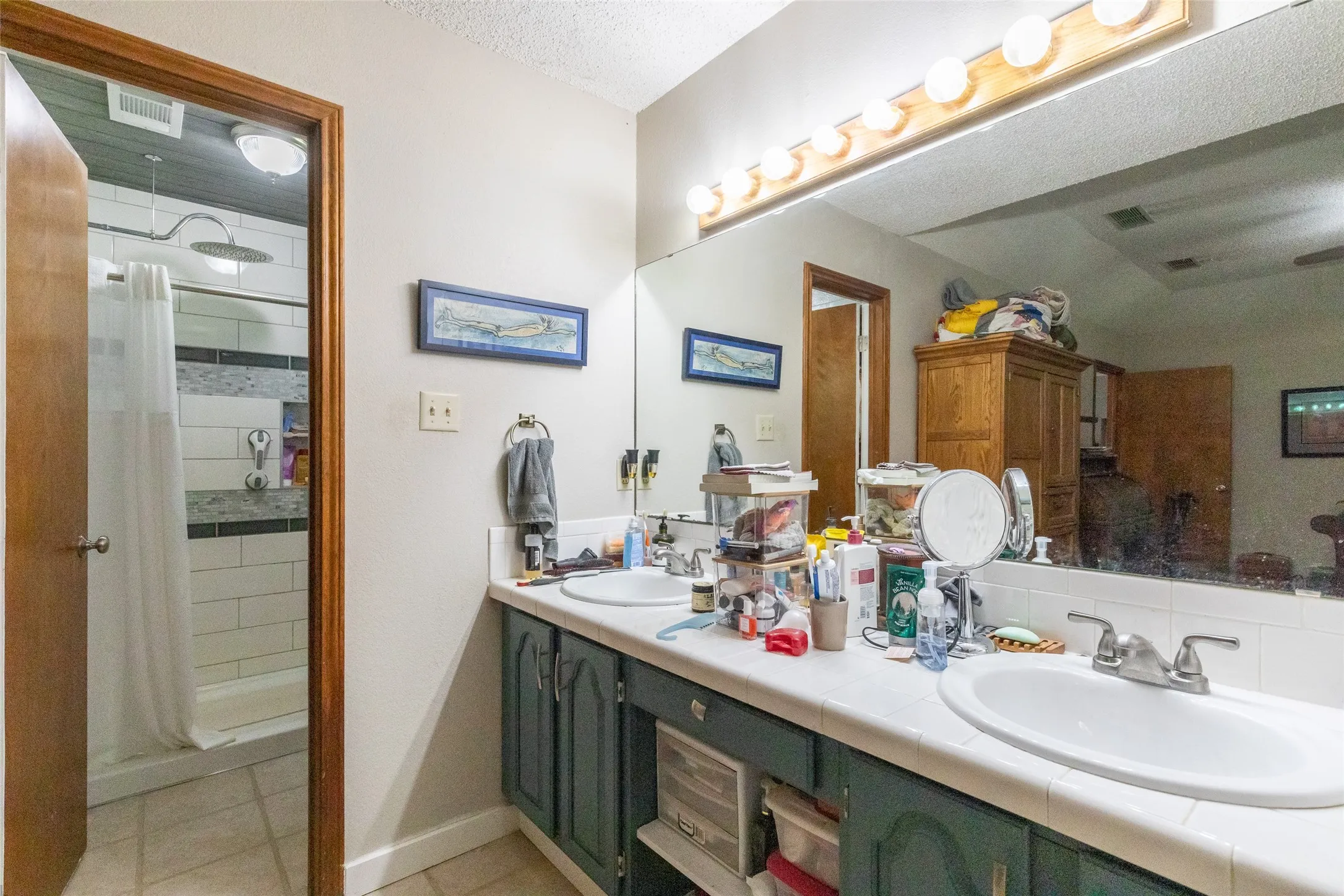 Bathroom featuring a dual-sink vanity with a white countertop and green cabinetry