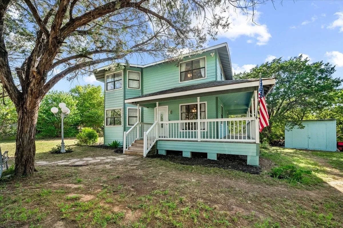 Two-story residence featuring a covered front porch with white railing, a light blue exterior, and multiple windows