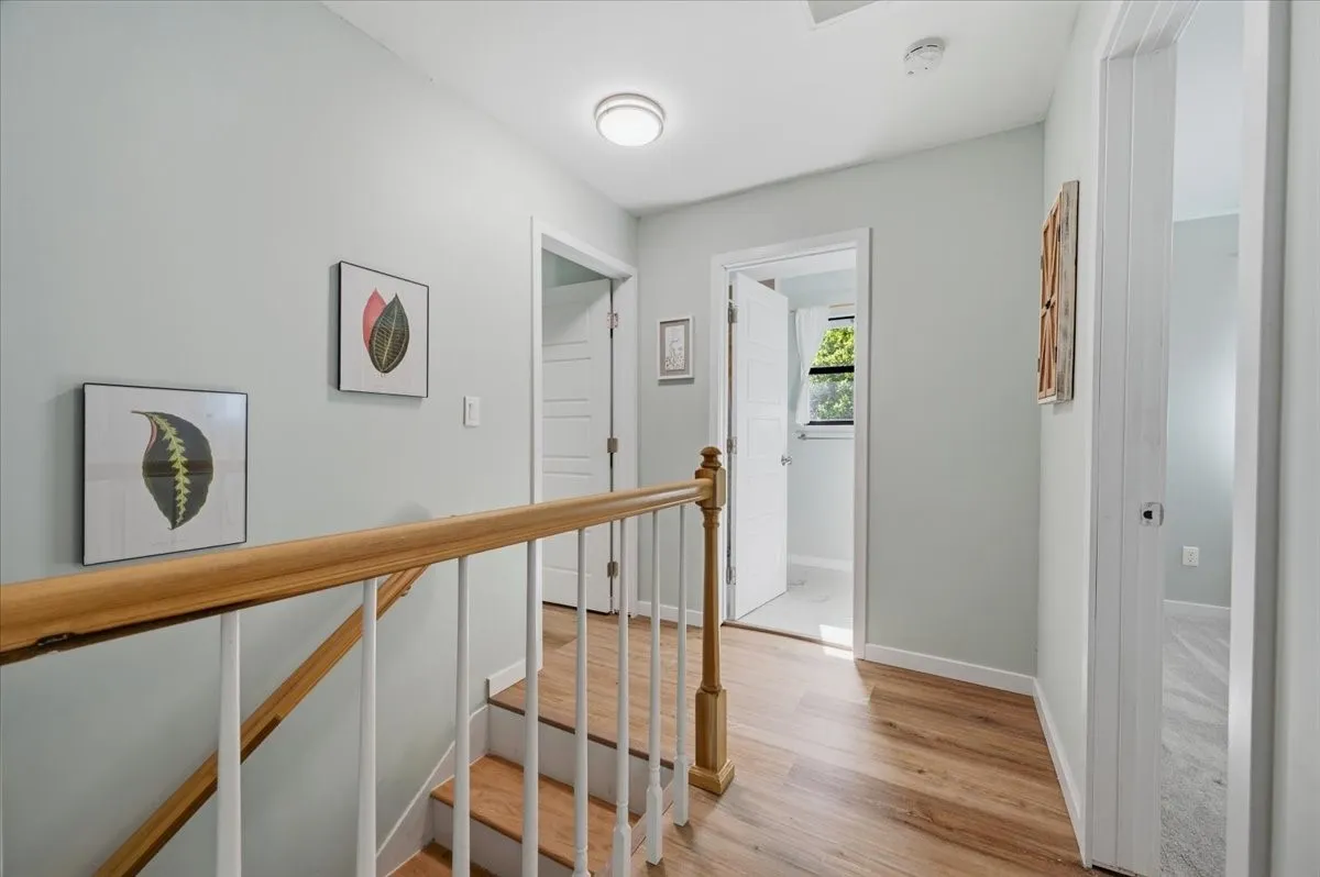 Staircase with wood-finish treads and risers, complemented by a natural wood handrail and white balusters