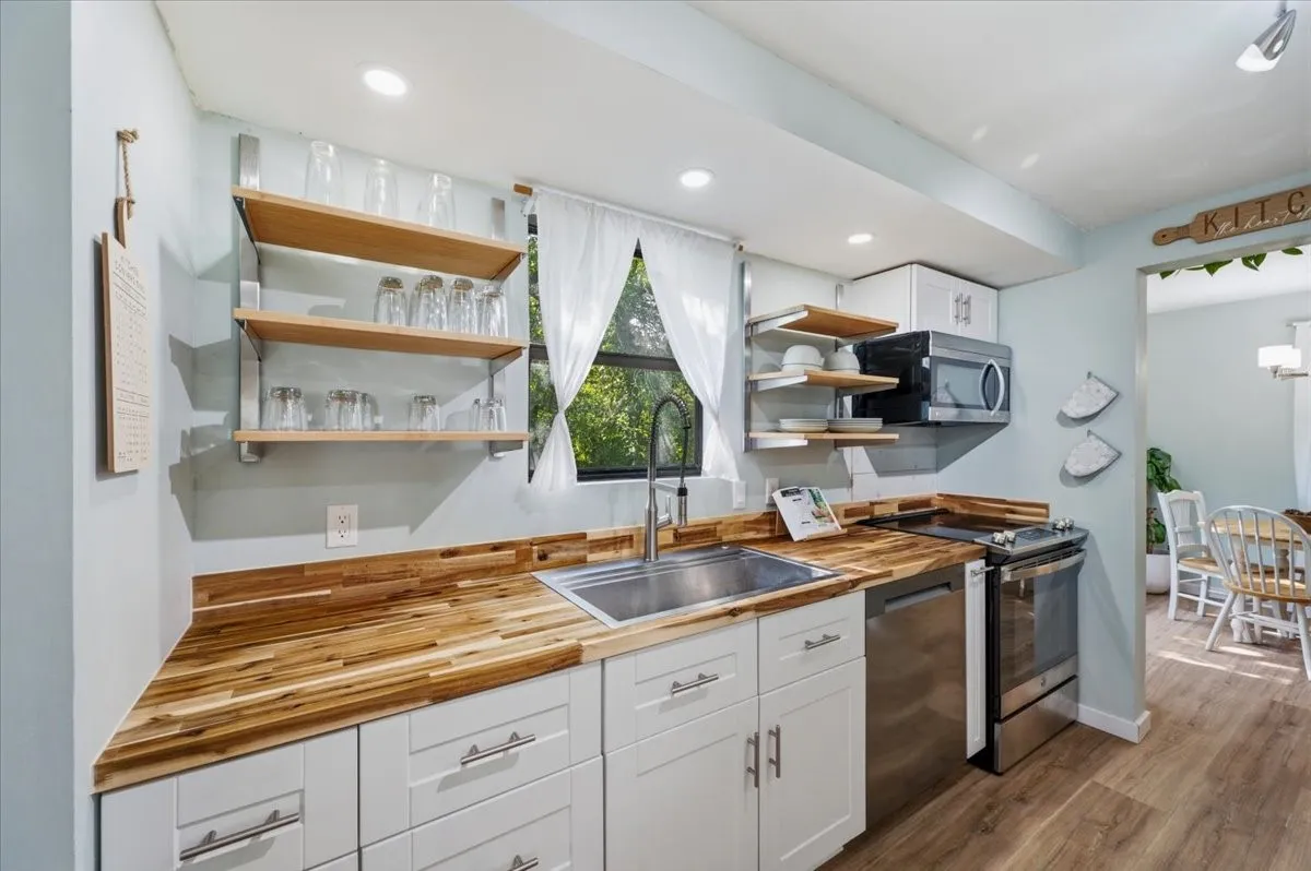 Kitchen featuring butcher block-style countertops and white shaker cabinetry