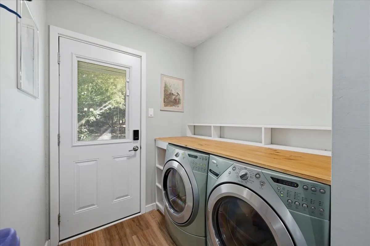 Dedicated laundry area featuring wood-finish flooring and a white paneled door with a glass insert