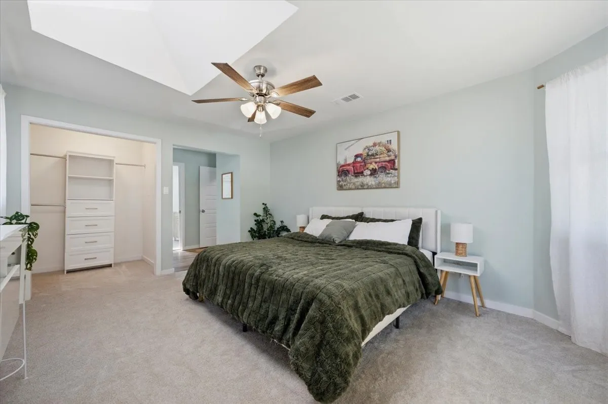 Carpeted bedroom with a tray ceiling and ceiling fan