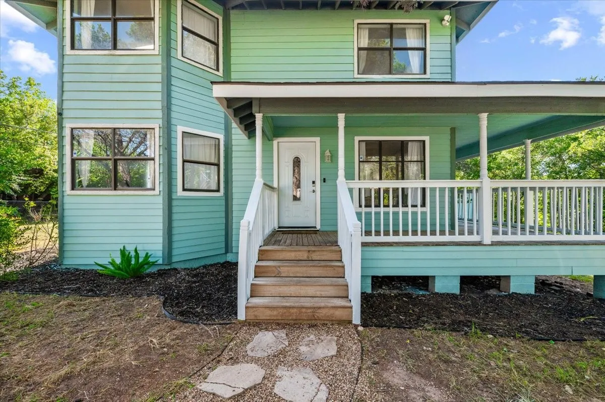 Two-story residence featuring a covered front porch with white railing, wooden steps, and a white front door with decorative glass inlay