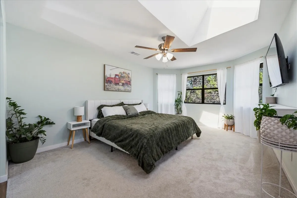 Recessed ceiling details with a ceiling fan, light blue wall paint, multiple windows, and light neutral carpeting