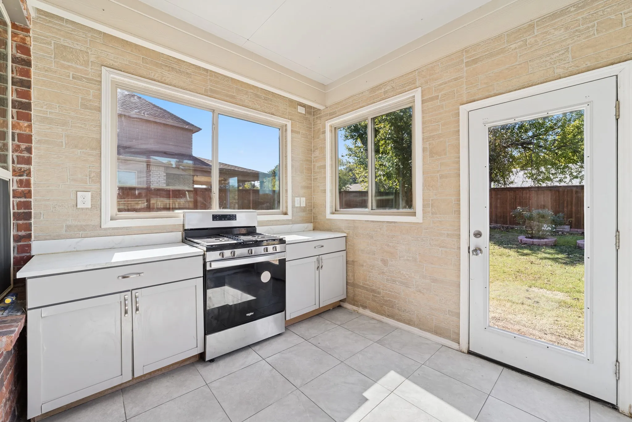 Patio kitchen featuring gas range, plenty of natural light, light tile patterned floors, and ornamental molding