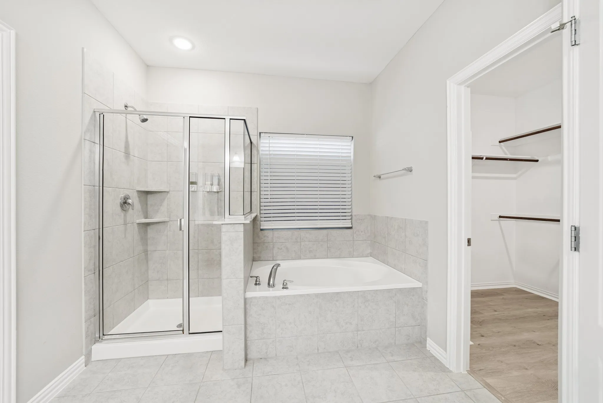 Master bathroom featuring light tile patterned flooring, a garden tub, a shower stall, and a spacious closet