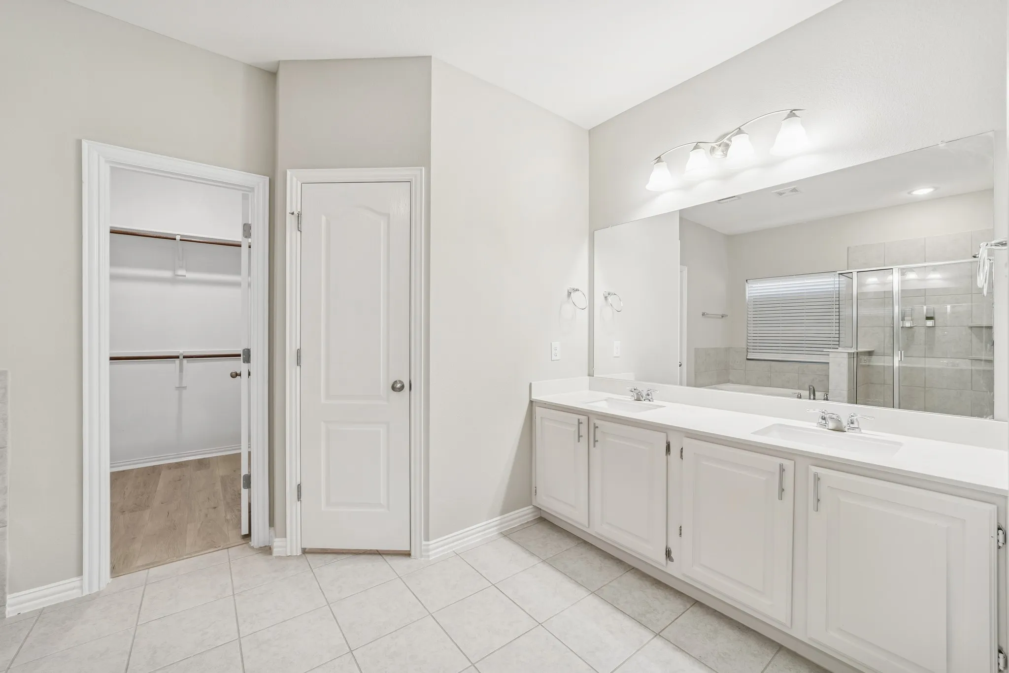 Master bathroom featuring double vanity, a stall shower, light tile patterned floors, and a walk in closet