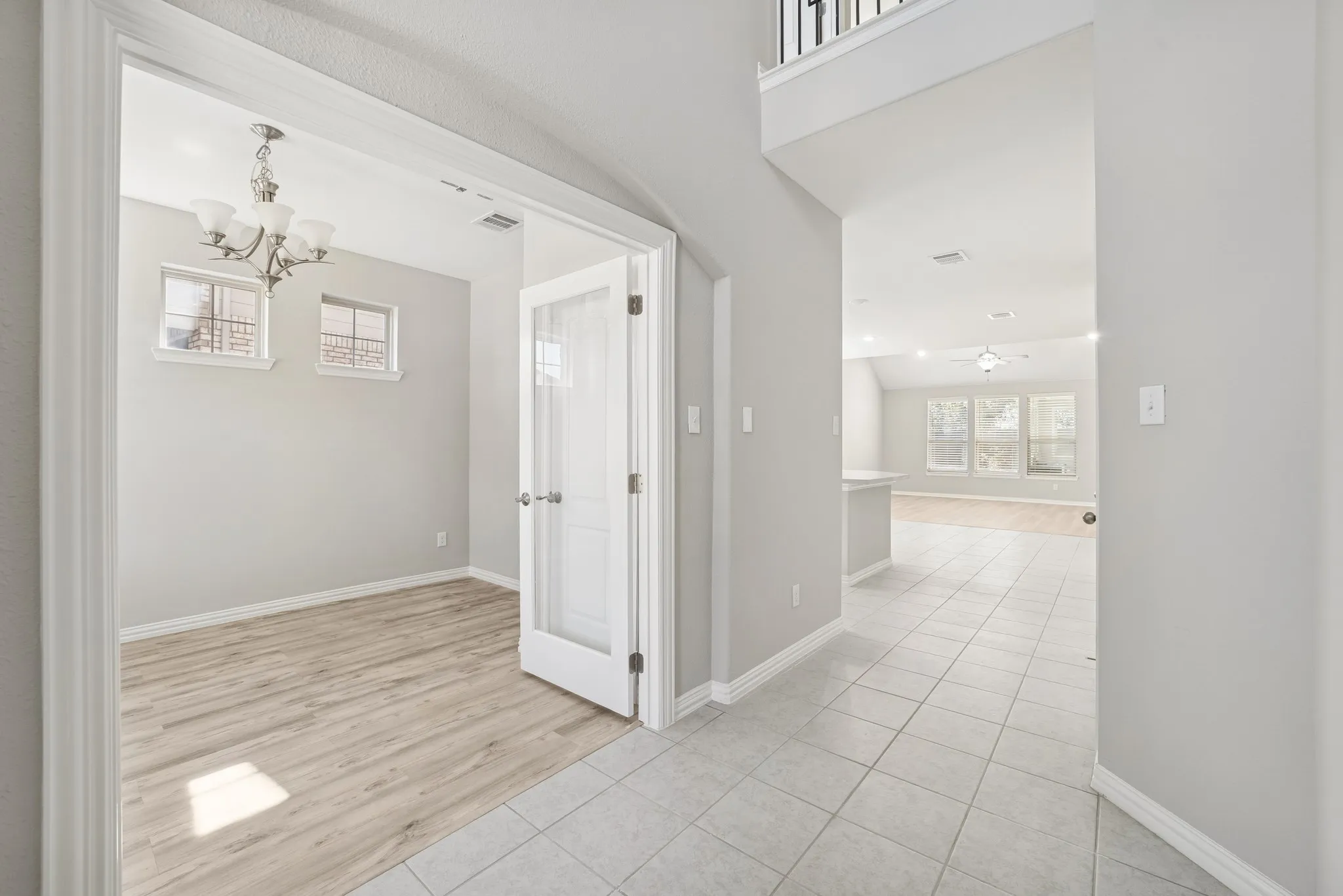 Corridor with light tile patterned floors, healthy amount of natural light, a chandelier, and a high ceiling