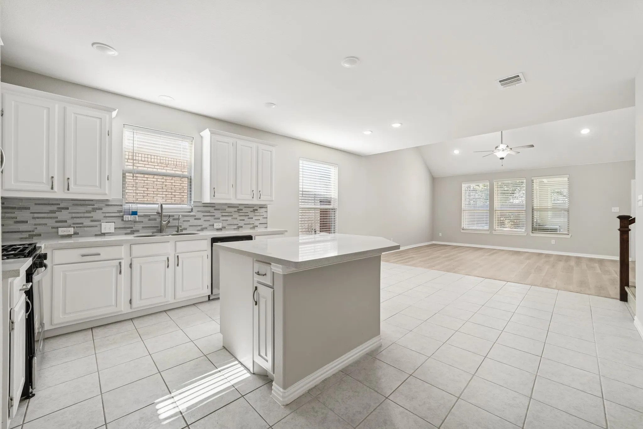 Kitchen with white cabinets, a center island, open floor plan, range with gas cooktop, and lofted ceiling