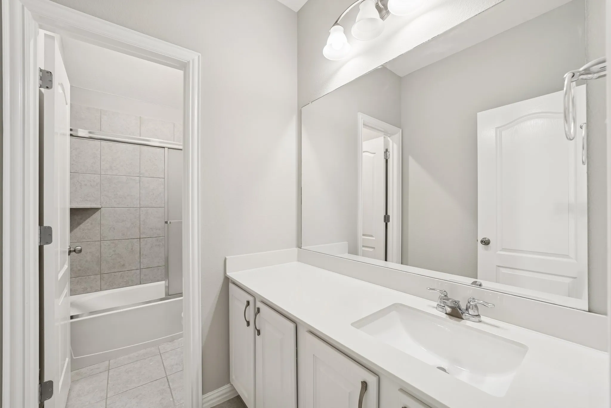 Full bath with vanity, bath / shower combo with glass door, and light tile patterned floors
