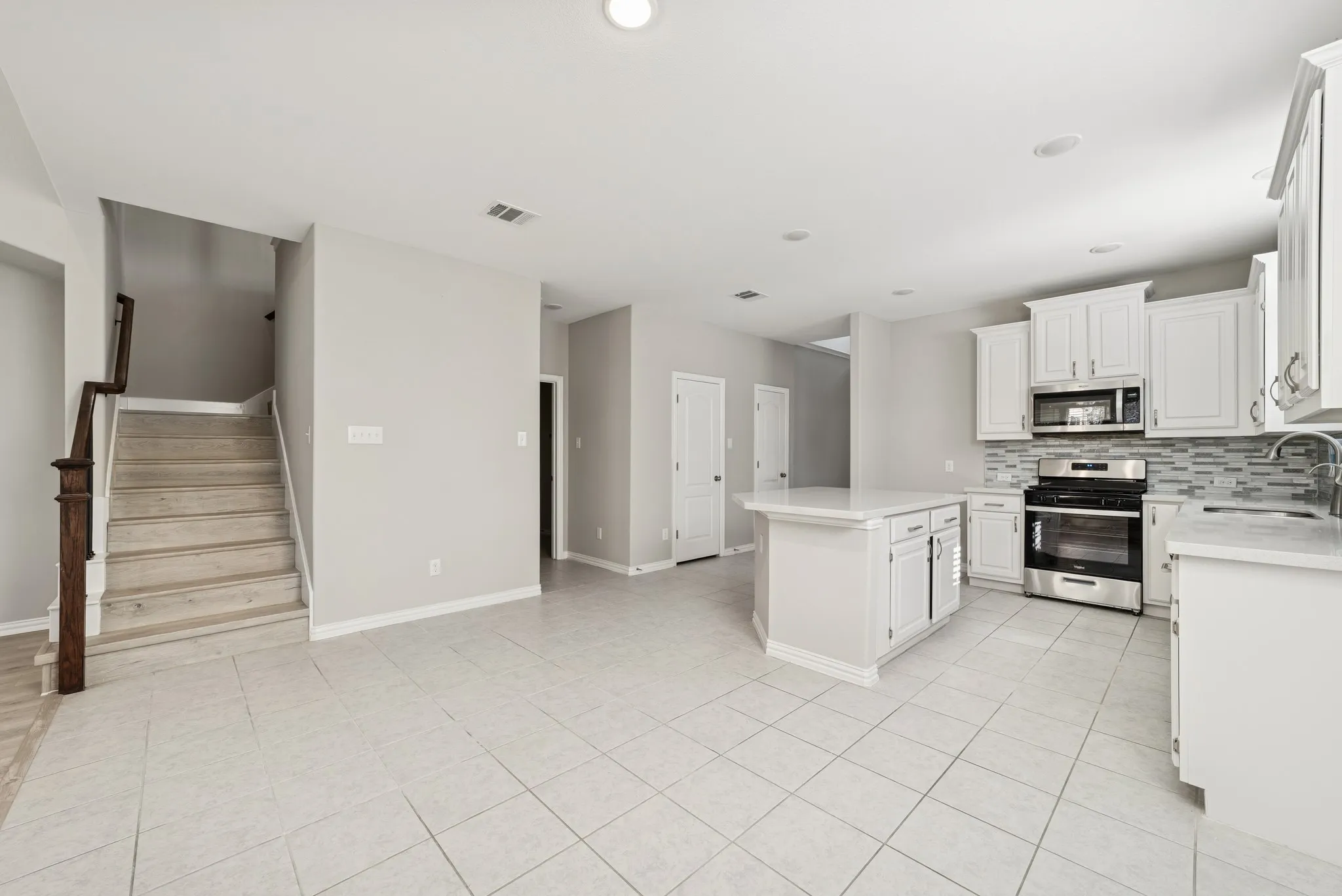 Kitchen featuring decorative backsplash, appliances with stainless steel finishes, white cabinets, a center island, and recessed lighting