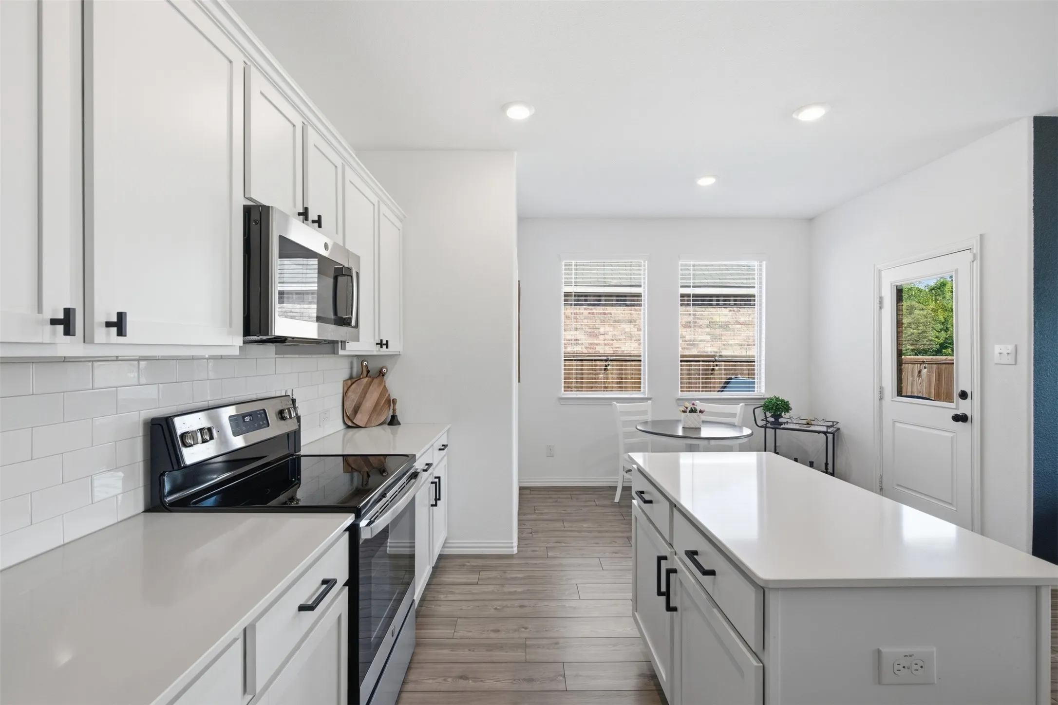Classic white subway tile backsplash and quartz countertops paired with the black hardware, and a versitial center island makes this kitchen beaitiful and functional