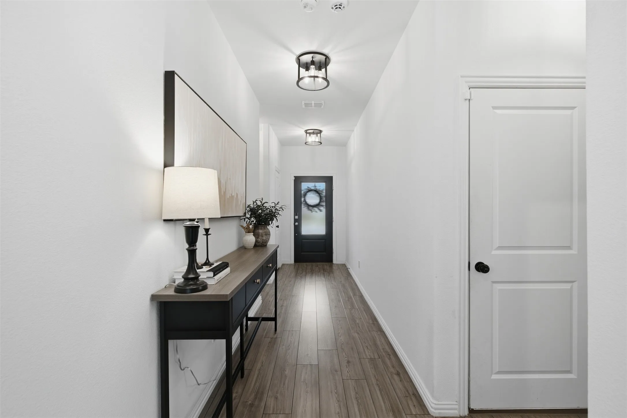 Fresh white walls, medium grey wood like floors, and customer selected black and clear glass light fixtures