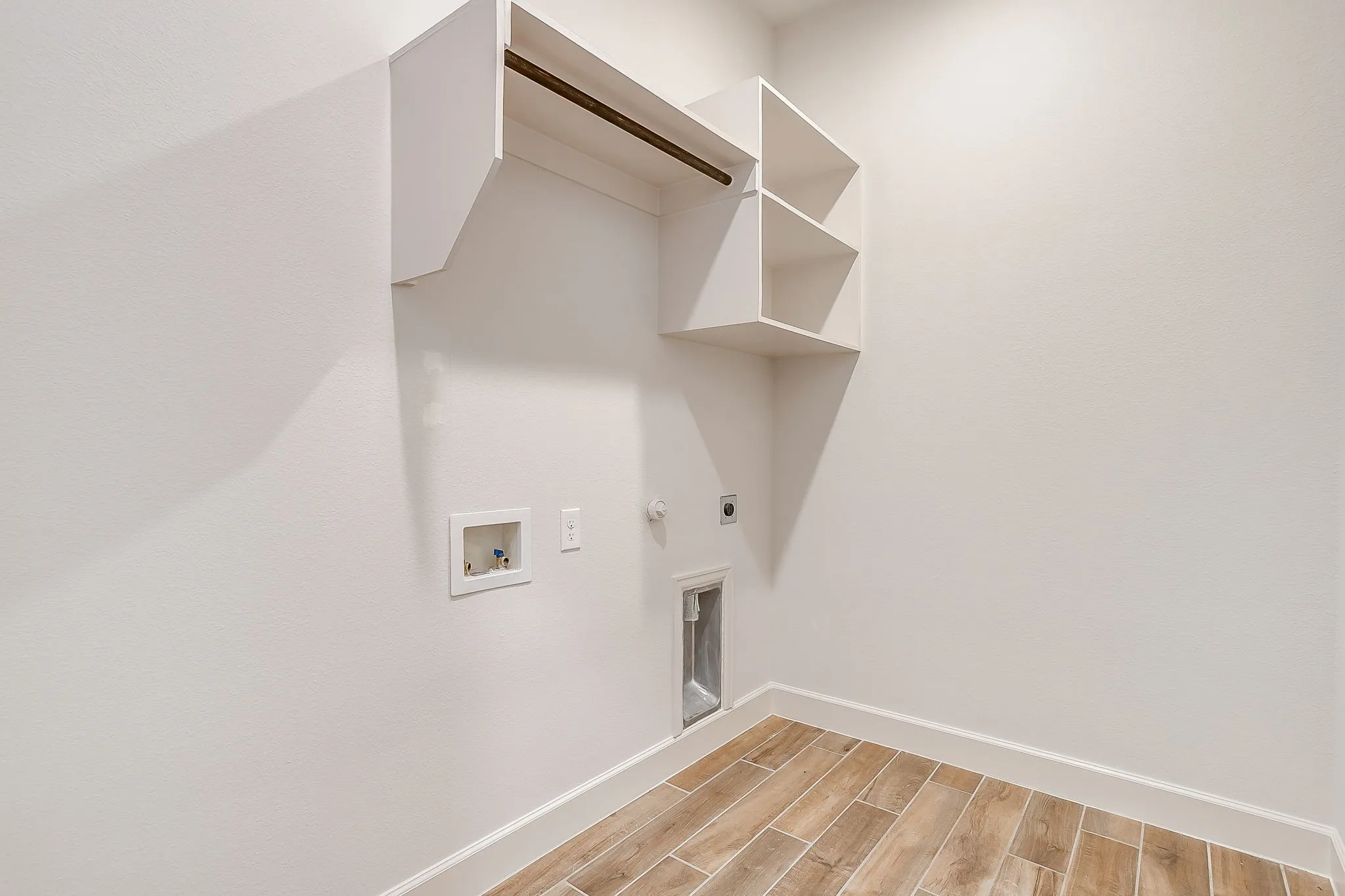 Laundry area featuring wood-finish flooring, built-in shelving, and a hanging rod