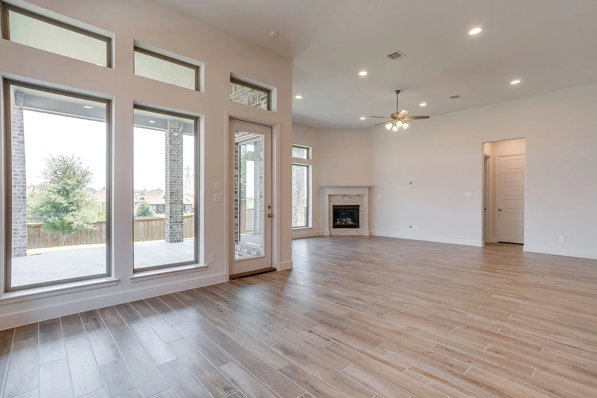 Spacious interior featuring wood-finish flooring, a contemporary fireplace with a stone surround, recessed lighting, and a ceiling fan
