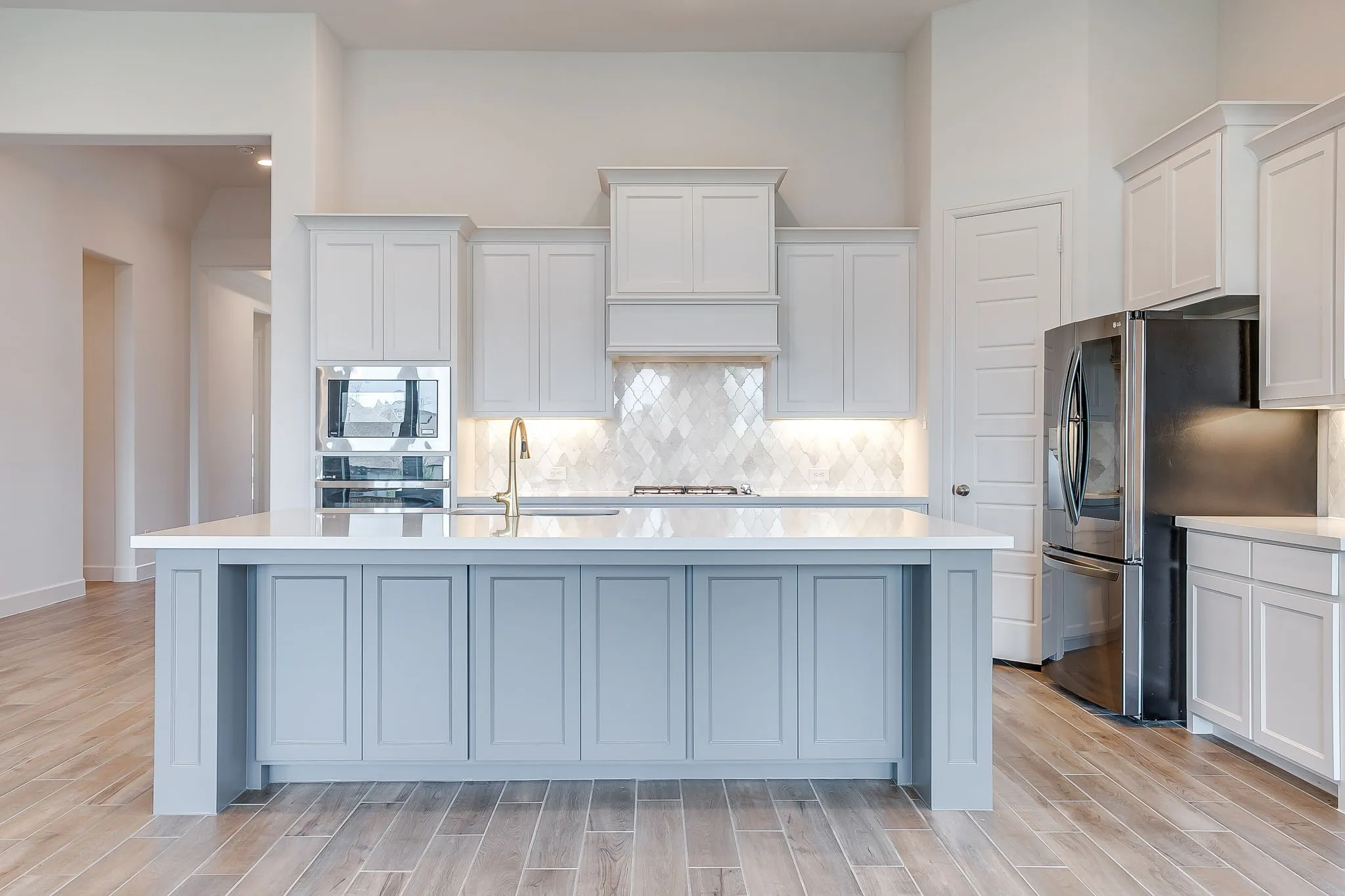 Contemporary kitchen featuring a large central island with light blue cabinetry and a white countertop