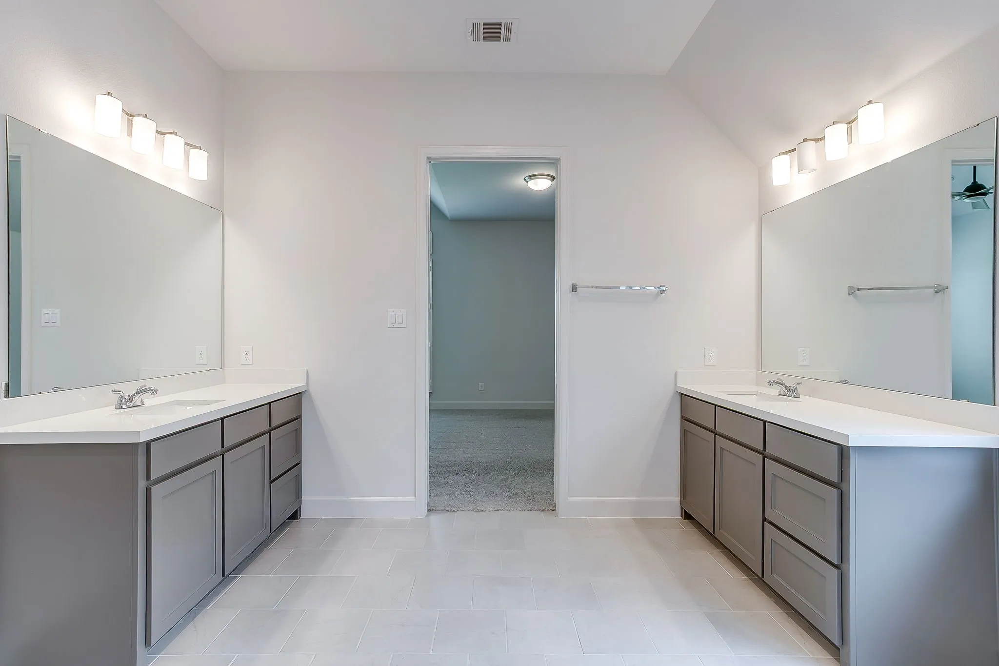 Dual vanity bathroom featuring light gray cabinetry, white countertops, rectangular mirrors, and contemporary lighting fixtures