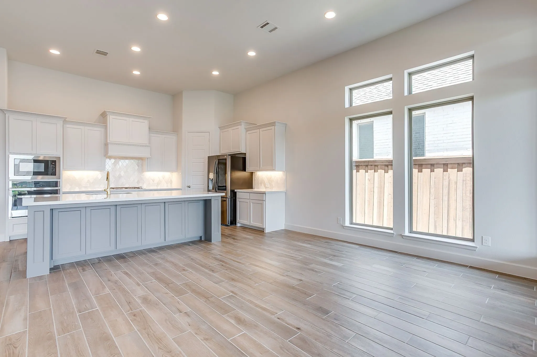 Open-concept living space featuring wood-look flooring, high ceilings, and recessed lighting