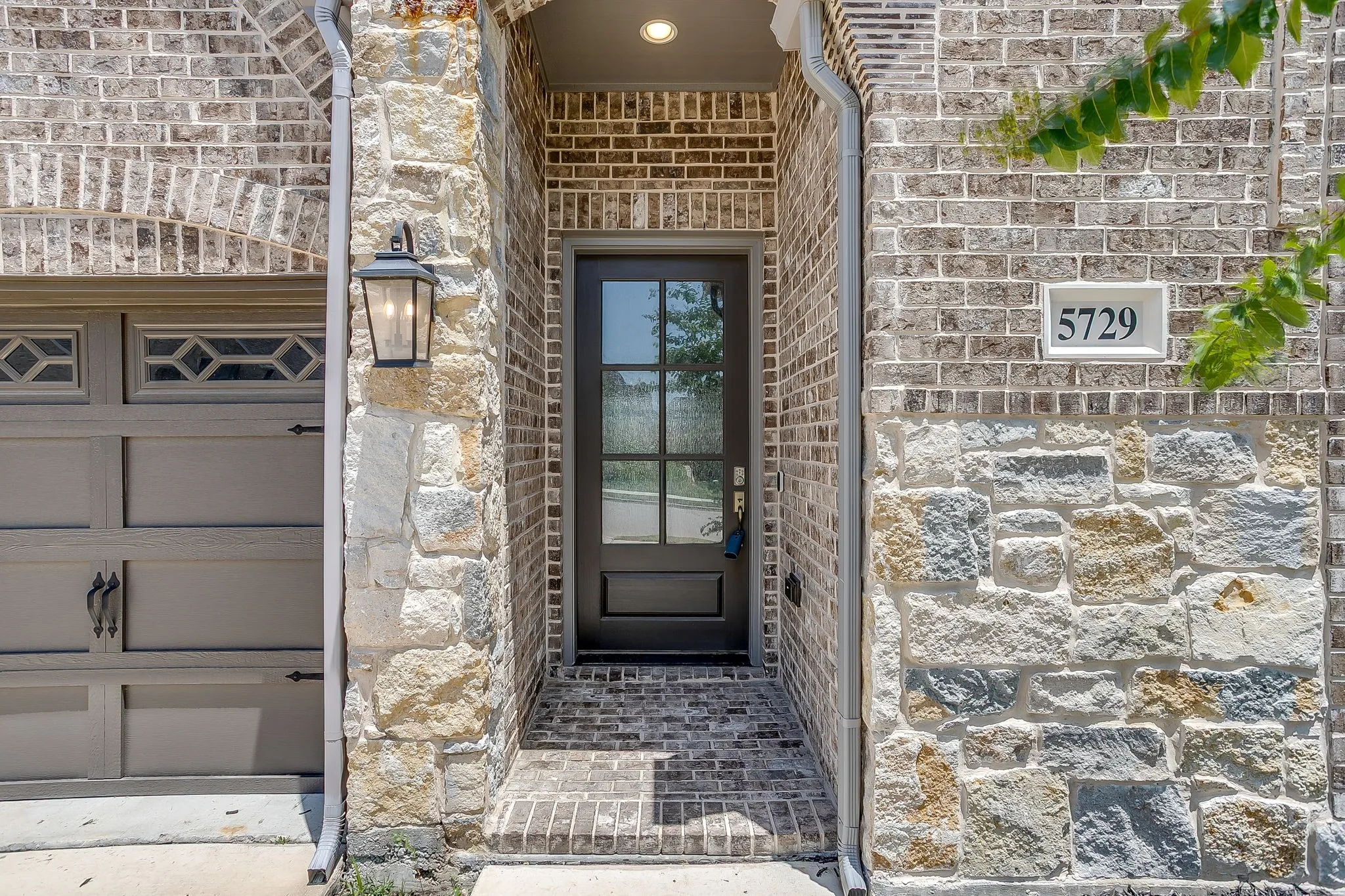 Stone and brick exterior featuring a dark wood-finish front door with glass lites