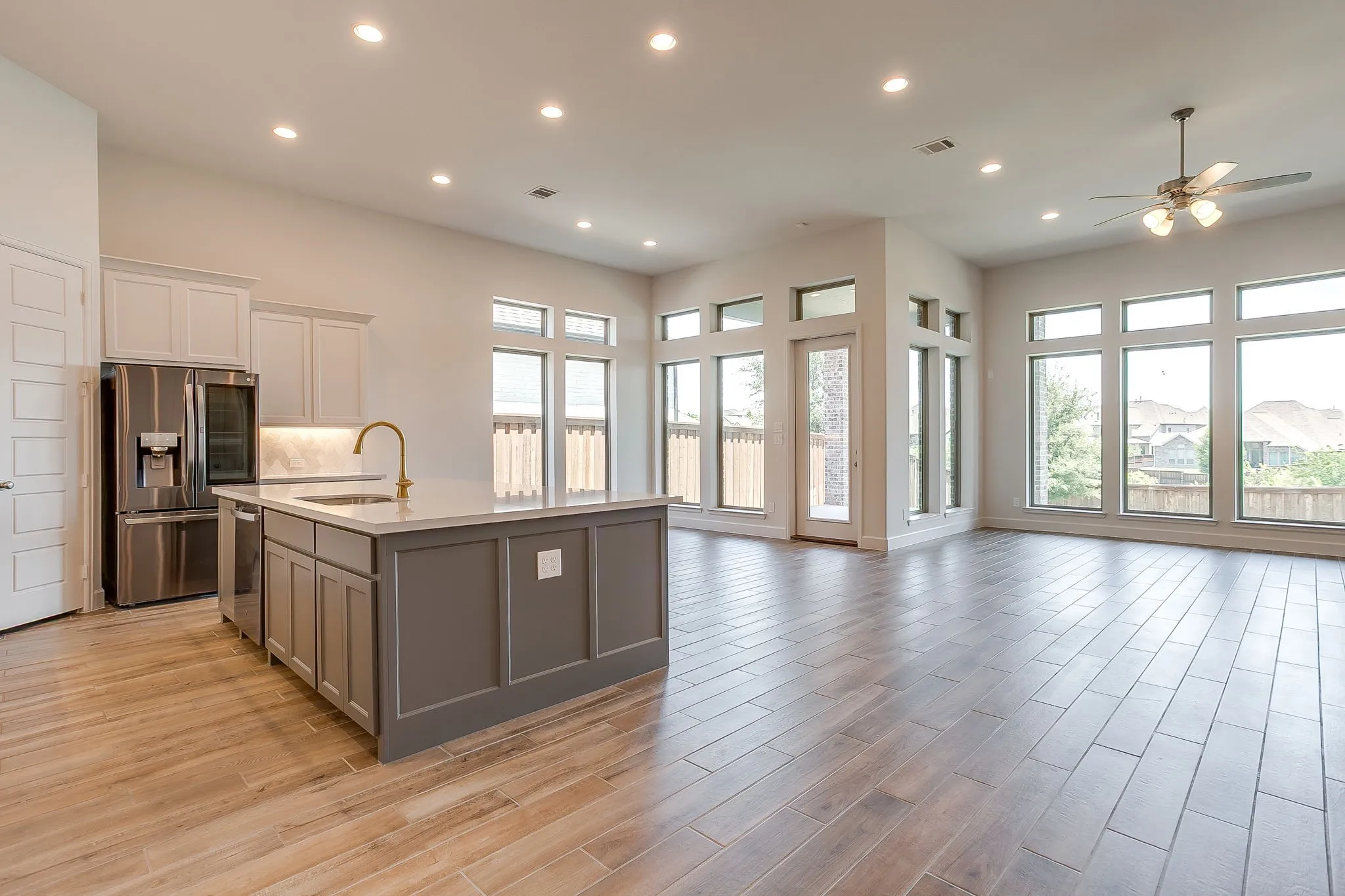 Open-concept interior featuring wood-finish flooring, recessed lighting, and a kitchen island with a gold-tone faucet