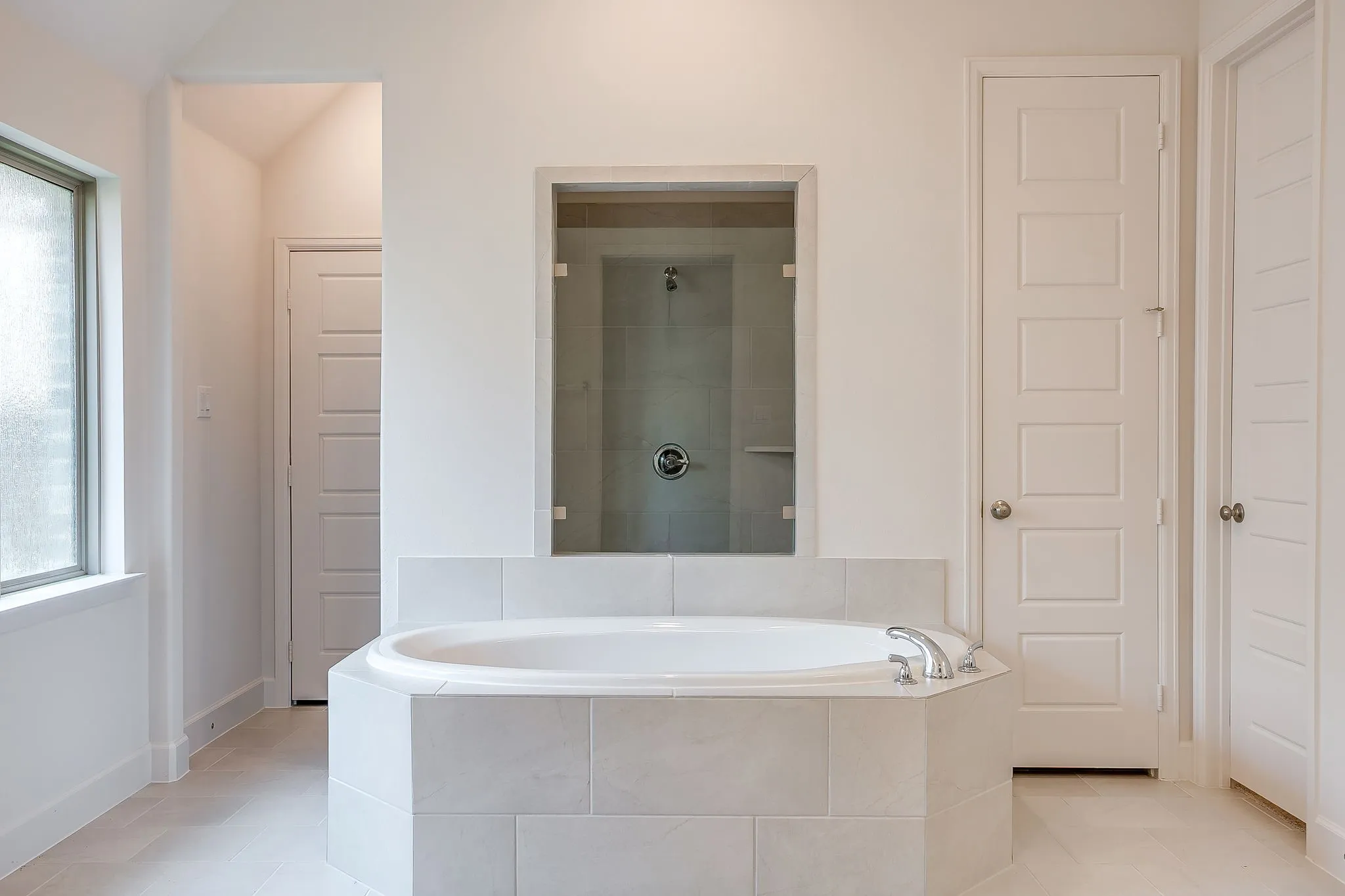 Freestanding soaking tub with tiled surround, chrome fixtures, and a clear glass enclosed shower