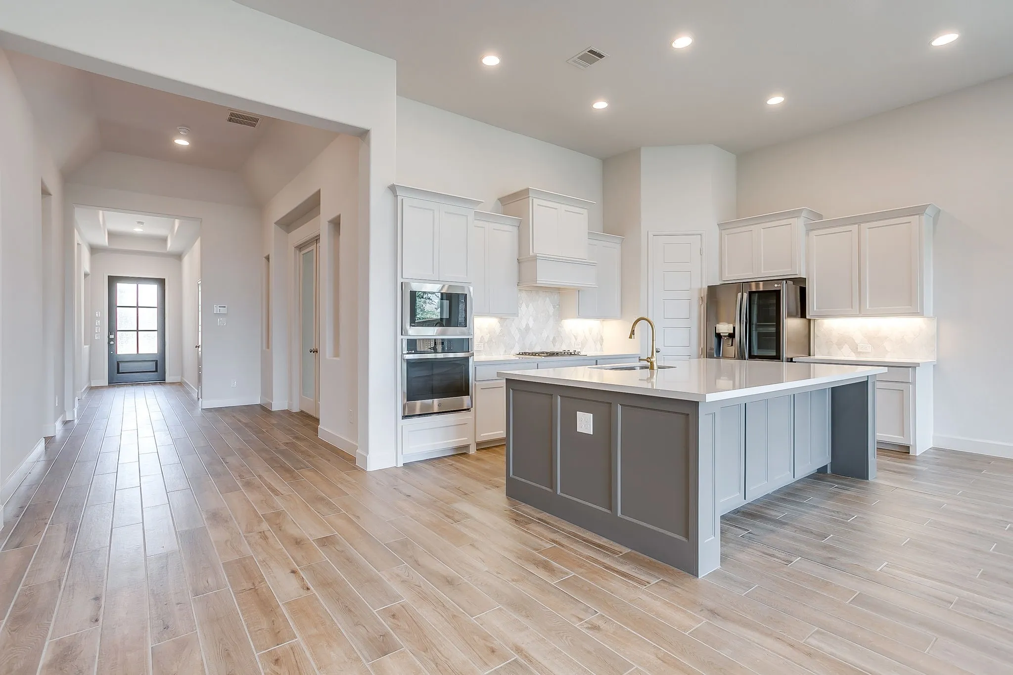 Open-concept kitchen featuring an expansive island with a white countertop and contrasting gray base