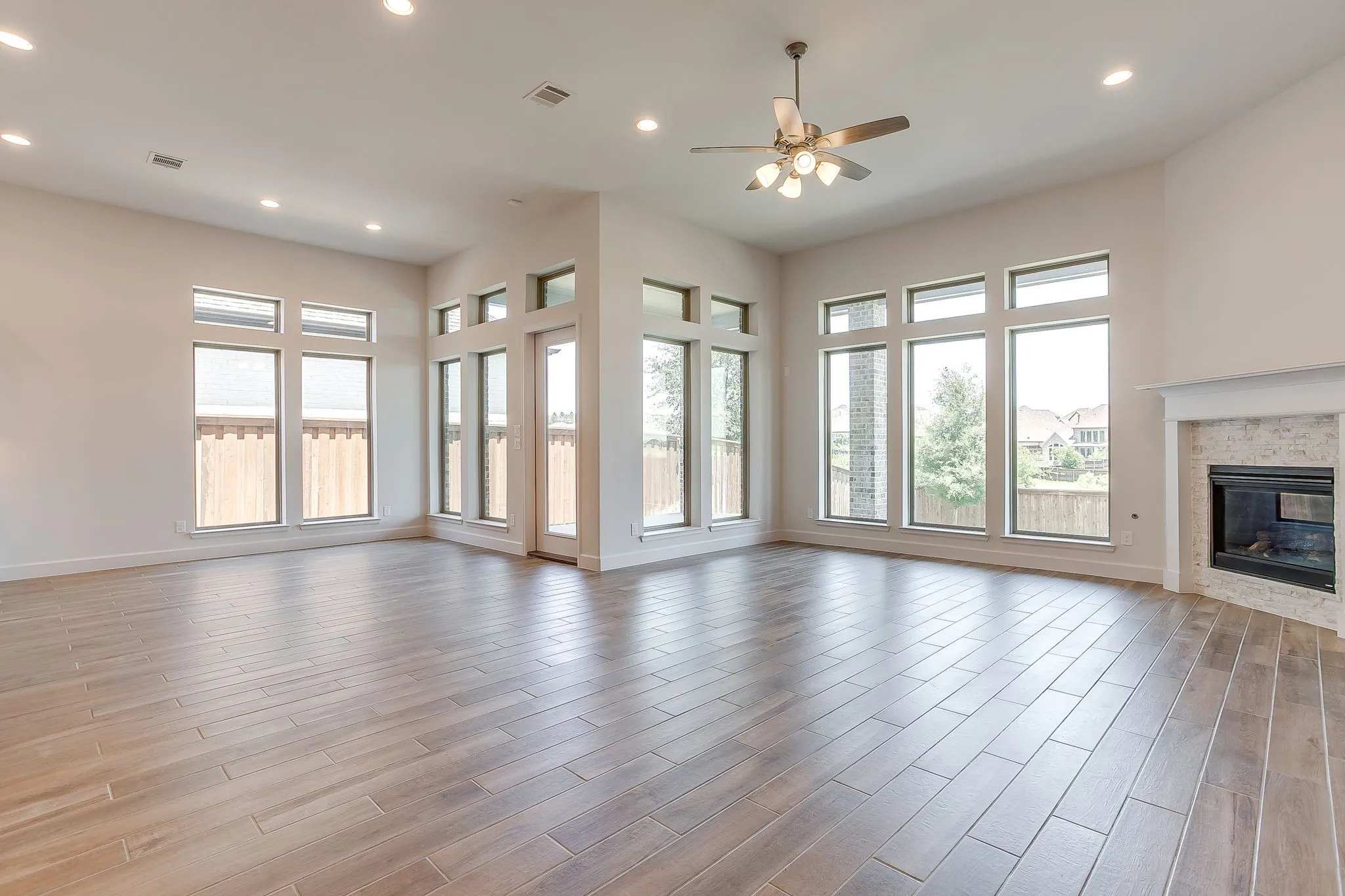 Spacious room featuring wood-finish tile flooring, recessed lighting, and a ceiling fan