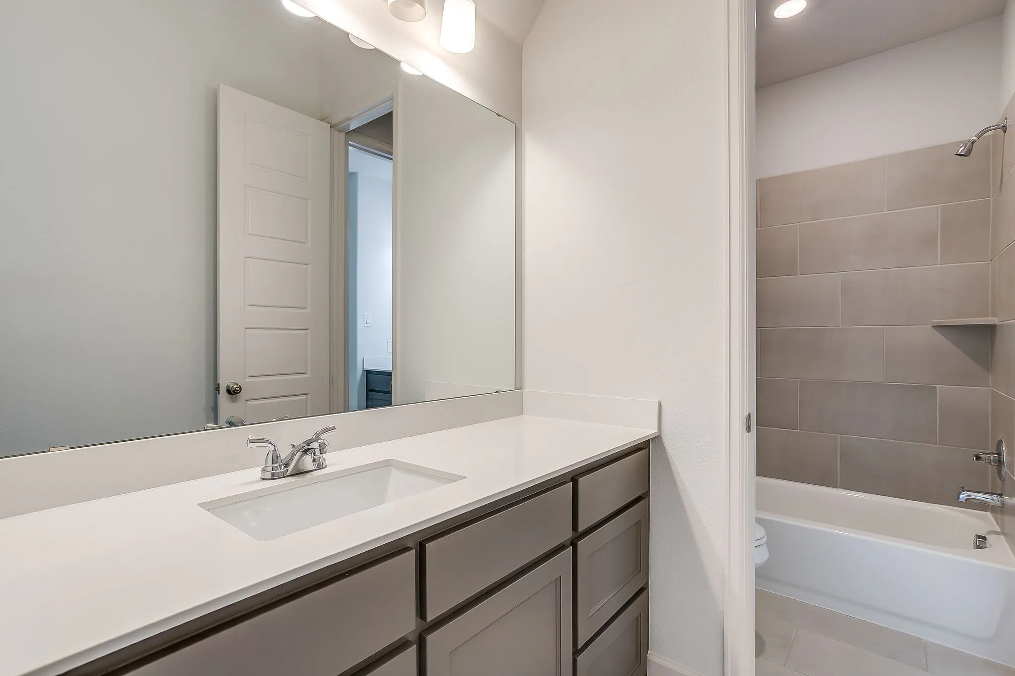 Bathroom featuring a white rectangular undermount sink, chrome faucet, and expansive vanity mirror