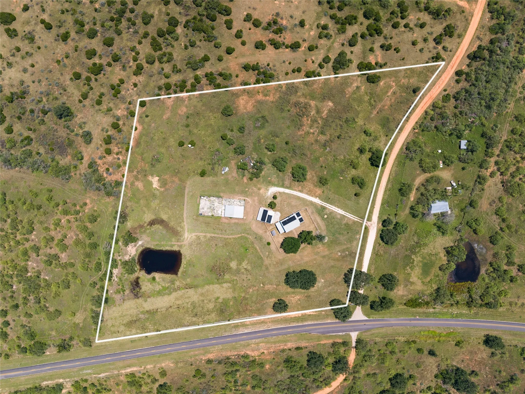 Aerial view highlighting the full 9.88 acre property boundary, including the home, outbuildings, and more