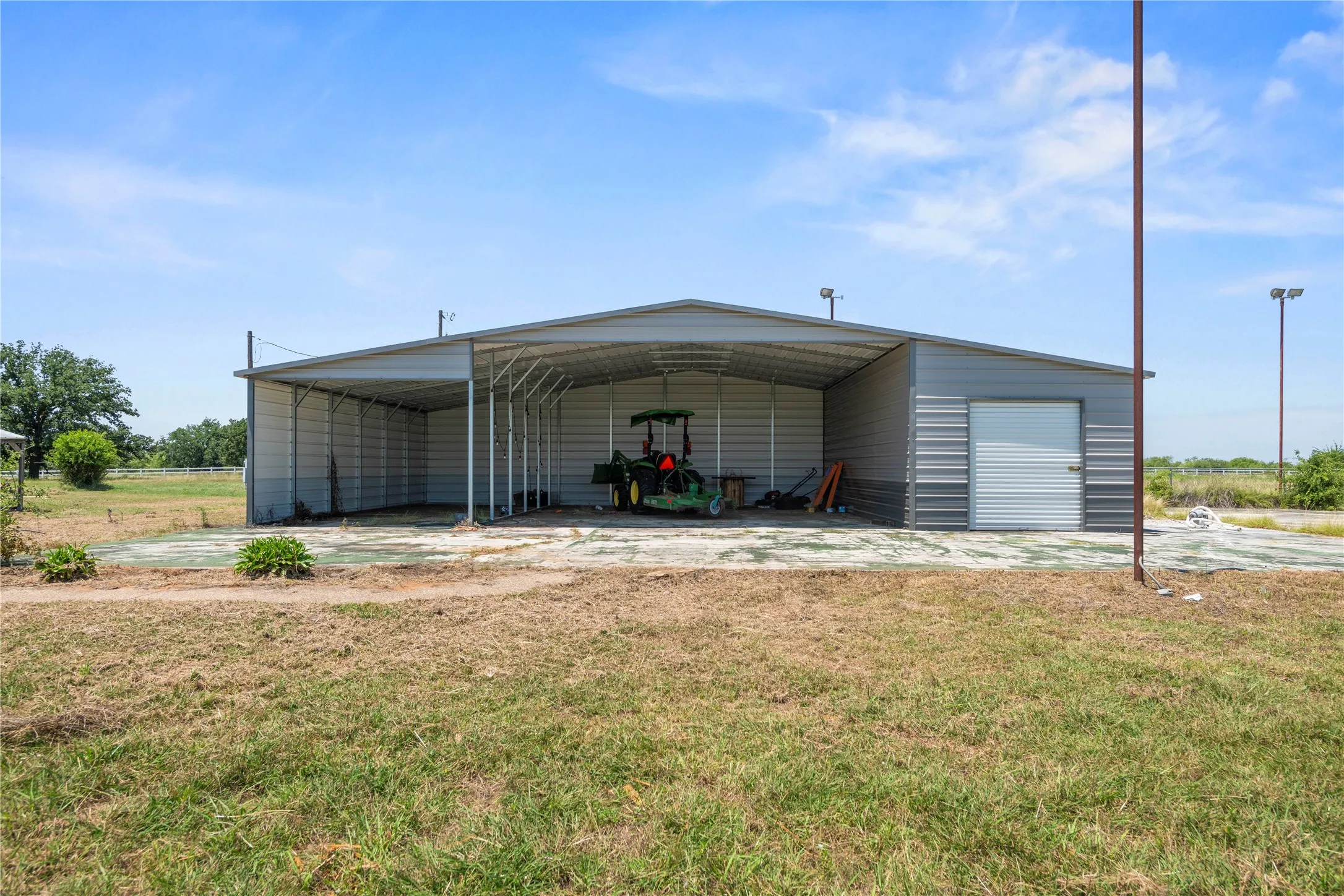 Large metal barn offers covered storage for equipment, tools, or a workshop setup, ideal for country living