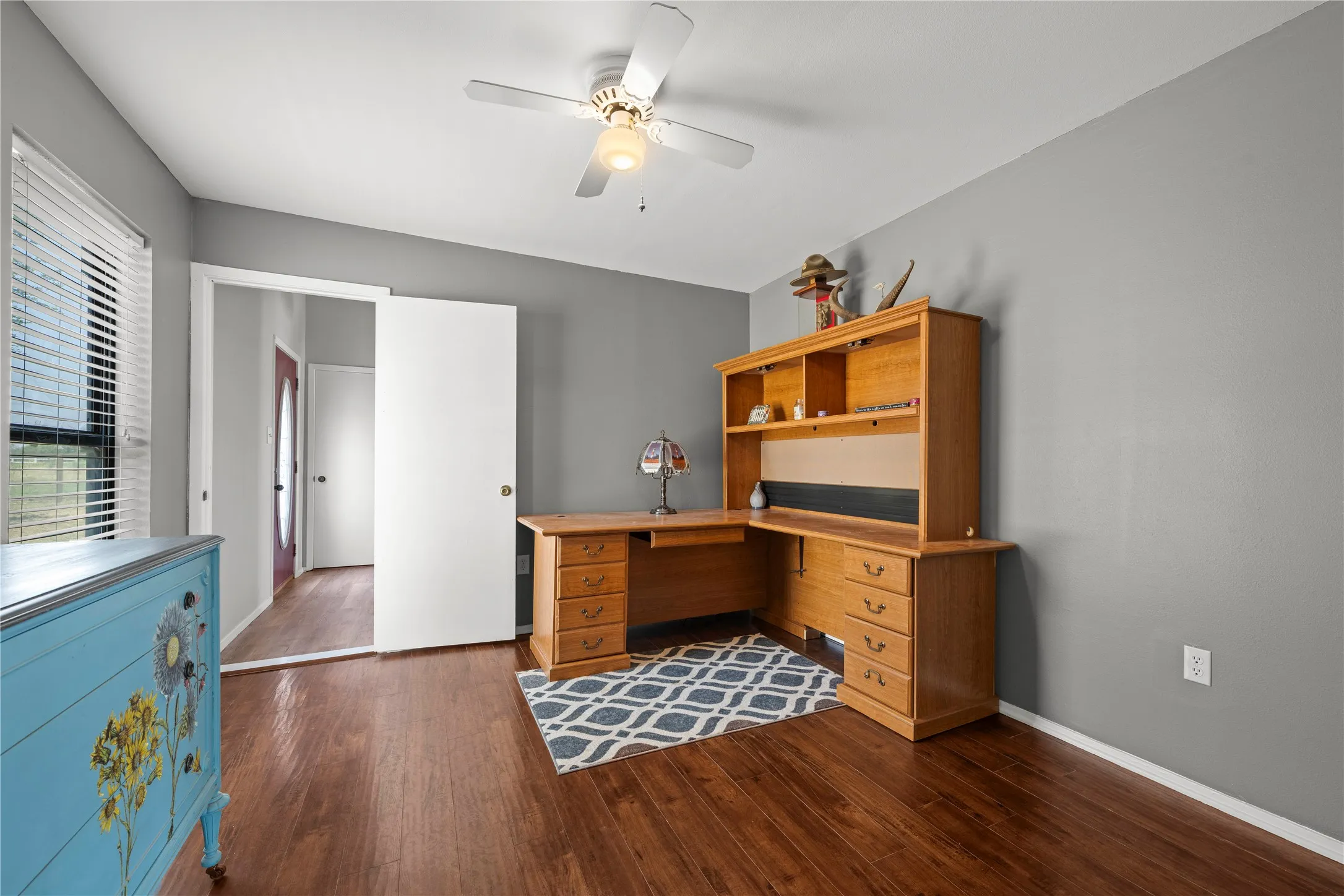 Versatile home office space with wood floors and a ceiling fan, ready to serve as a study, workspace, or extra bedroom.