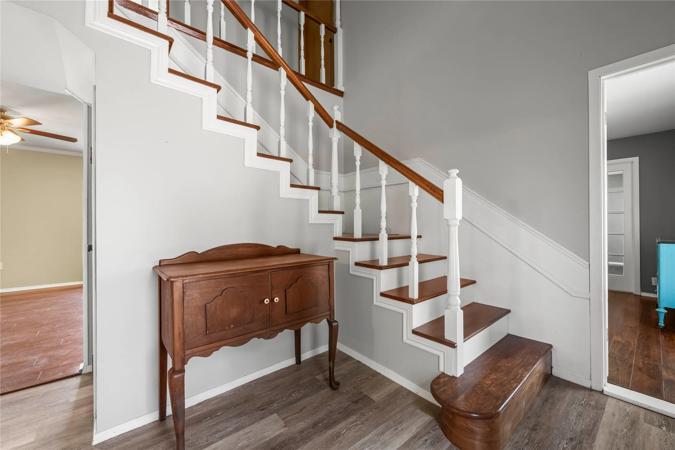 Charming staircase with white balusters and warm wood railings creates a welcoming entry into this spacious two story home.