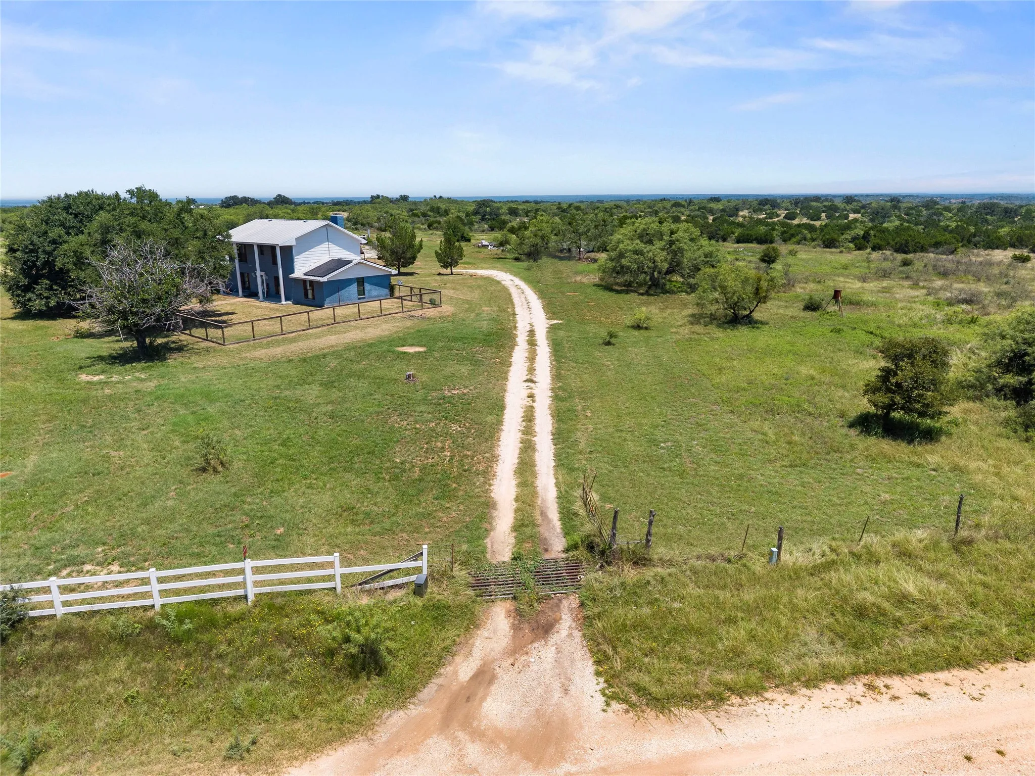 Long private driveway with cattle guard entrance leads to this acreage retreat, surrounded by mature trees and open pasture