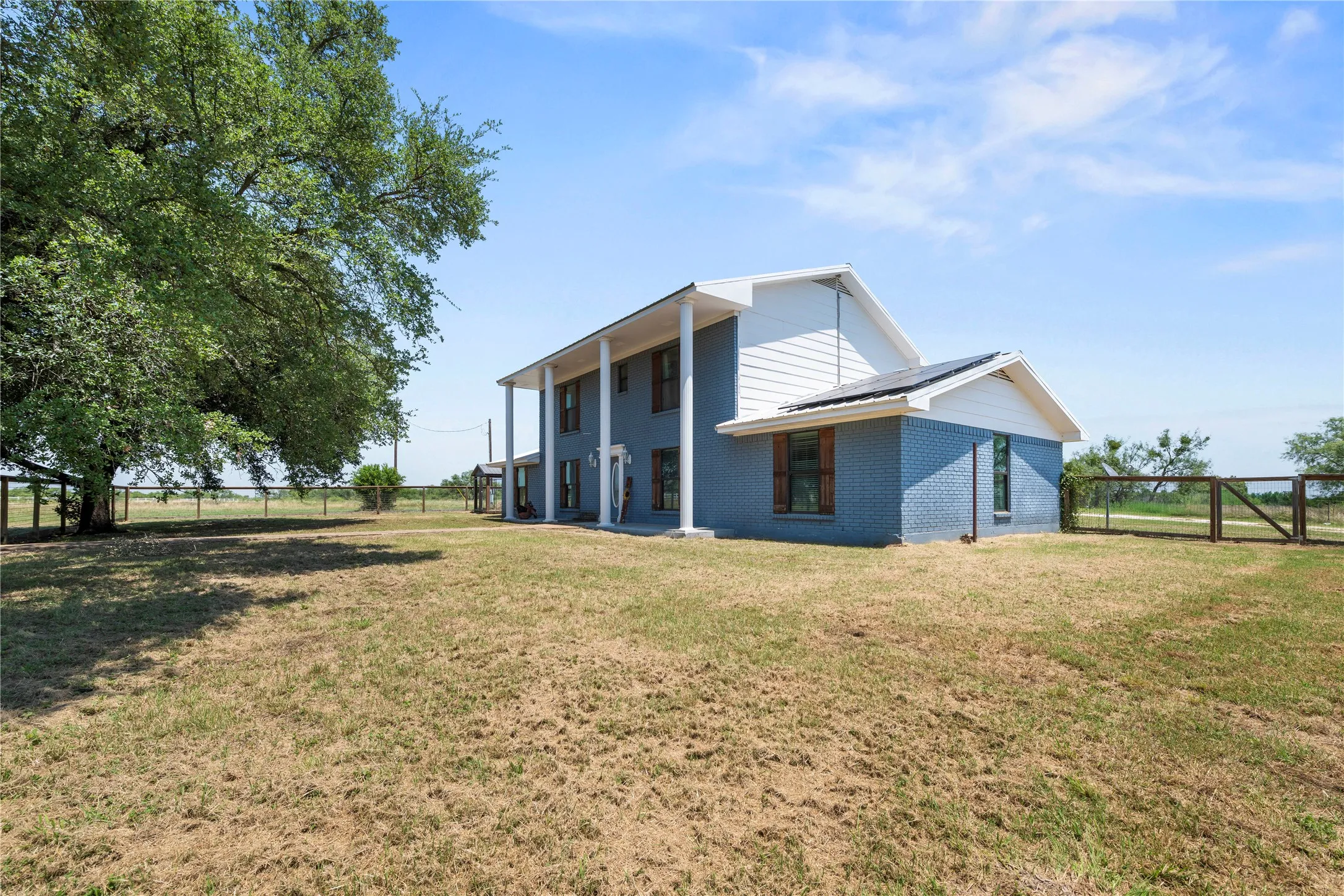 Side exterior view highlighting the metal roof, solar panels, and spacious grounds surrounding this 5 bedroom home.