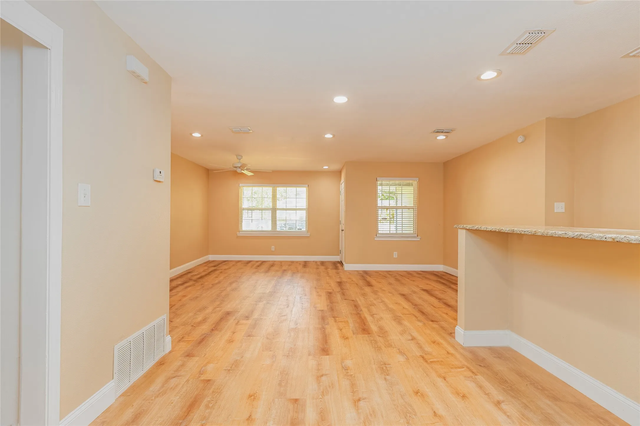 Recessed lighting, LVP flooring, ceiling fan, and a breakfast bar with a stone-finish countertop